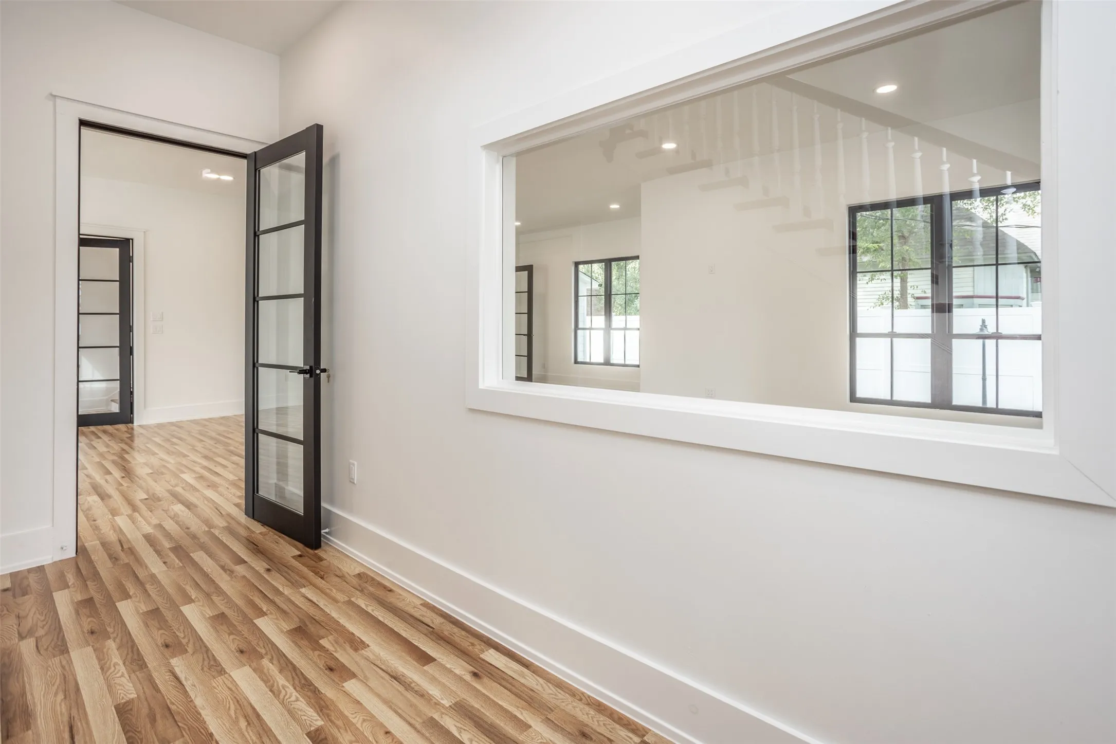 Interior space featuring wood-finish flooring, framed glass paneled doors, and an expansive window with white trim casing