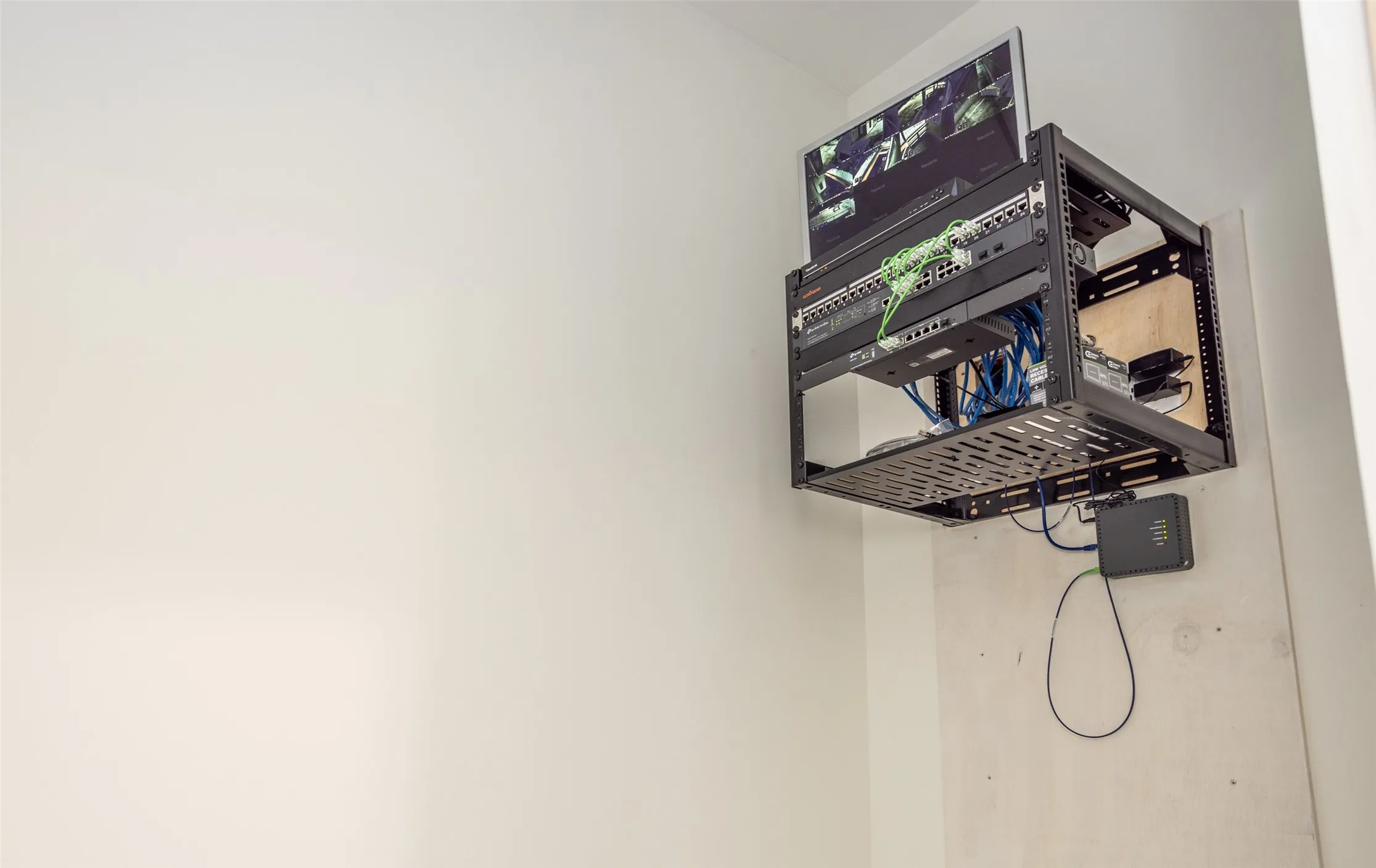 Wall-mounted server rack featuring organized networking hardware and an integrated monitor mount