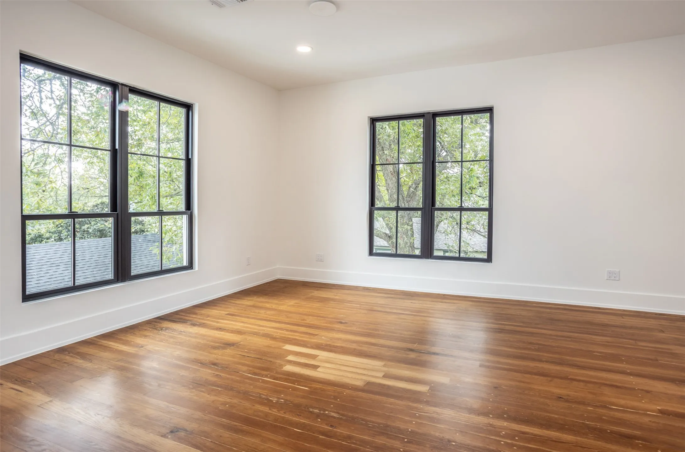 Spacious interior featuring wood-finish flooring, recessed lighting, oversized windows