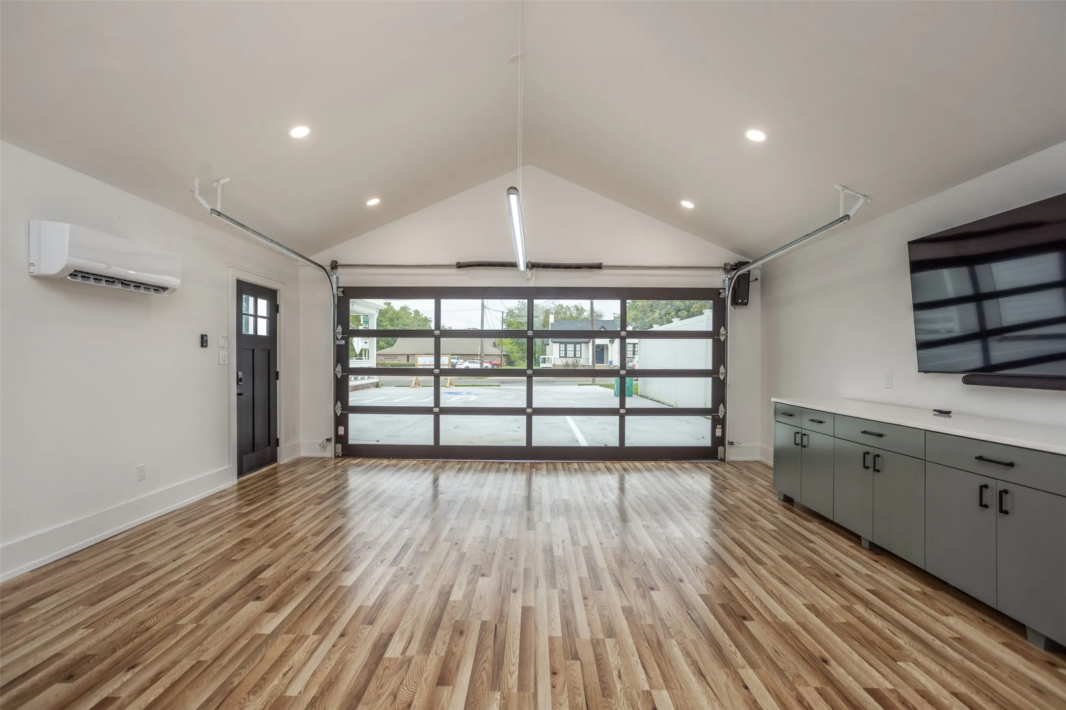 Interior space featuring wood-finish flooring, two large interior windows, and a framed glass paneled door