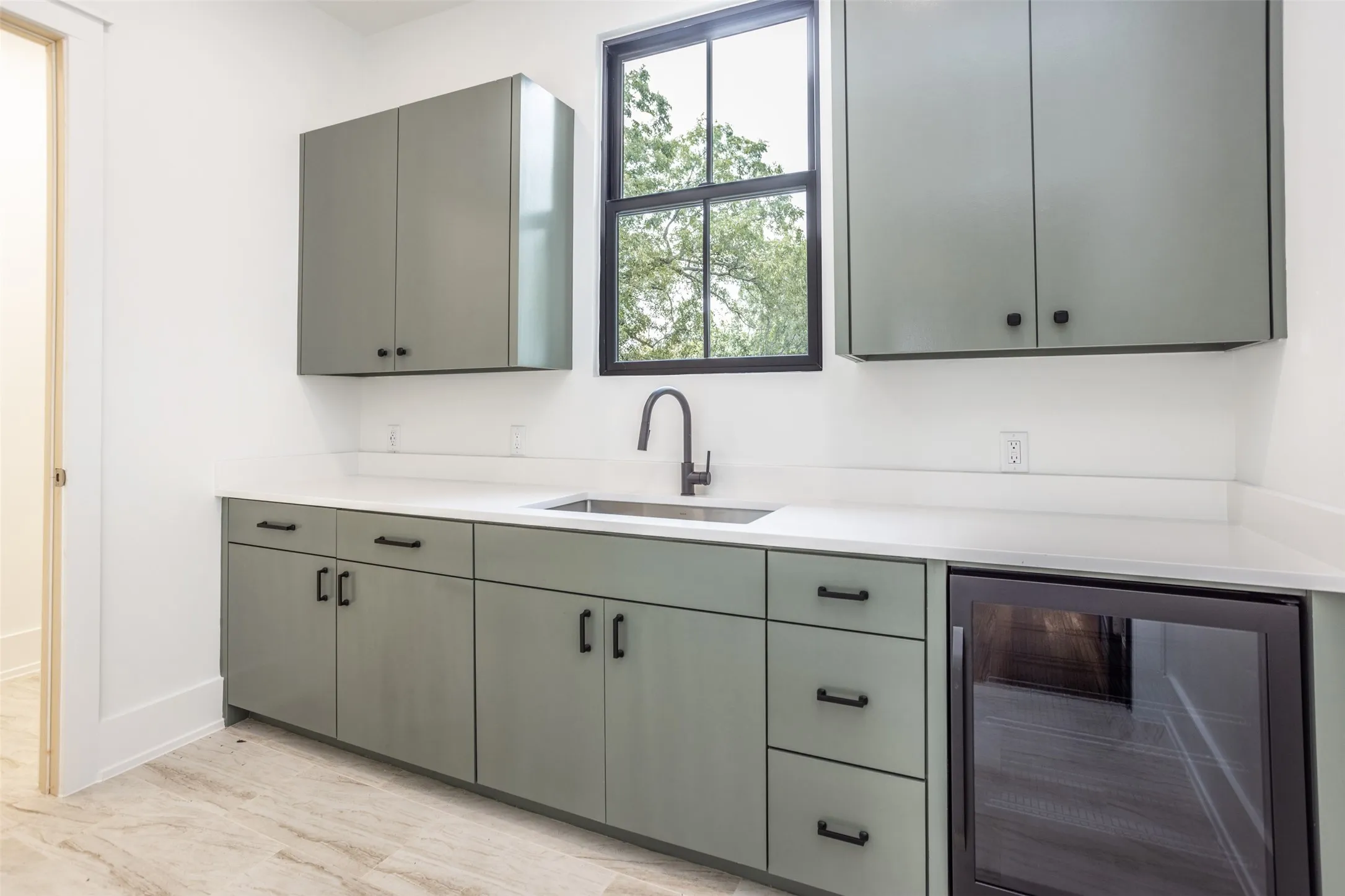 Custom cabinetry, countertops, stainless steel sink, and a built-in glass-door beverage refrigerator