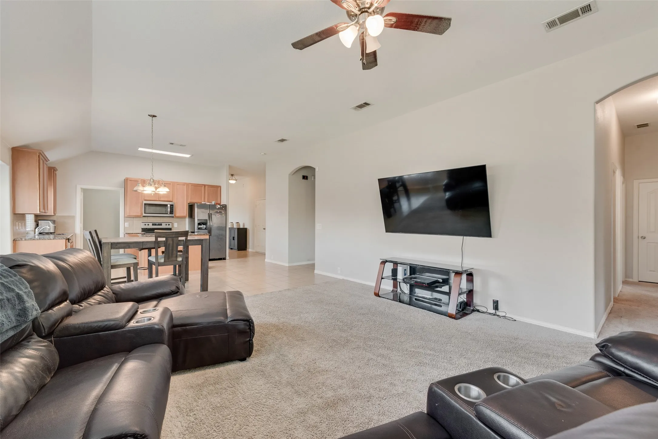 Open-concept interior featuring vaulted ceilings, neutral wall tones, recessed lighting, and a ceiling fan!