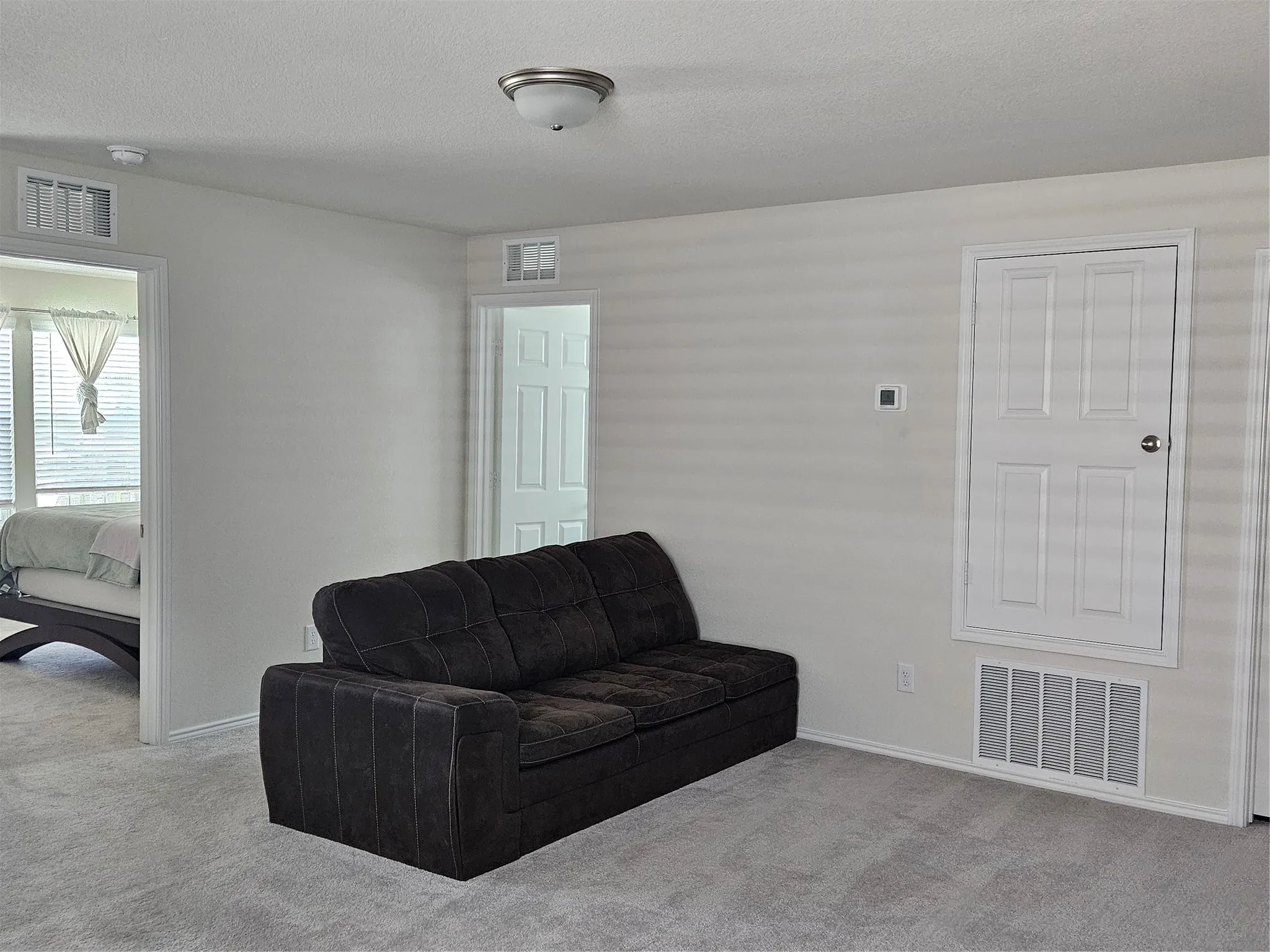 Interior room featuring neutral wall-to-wall carpeting, white interior doors, and a built-in wall access panel