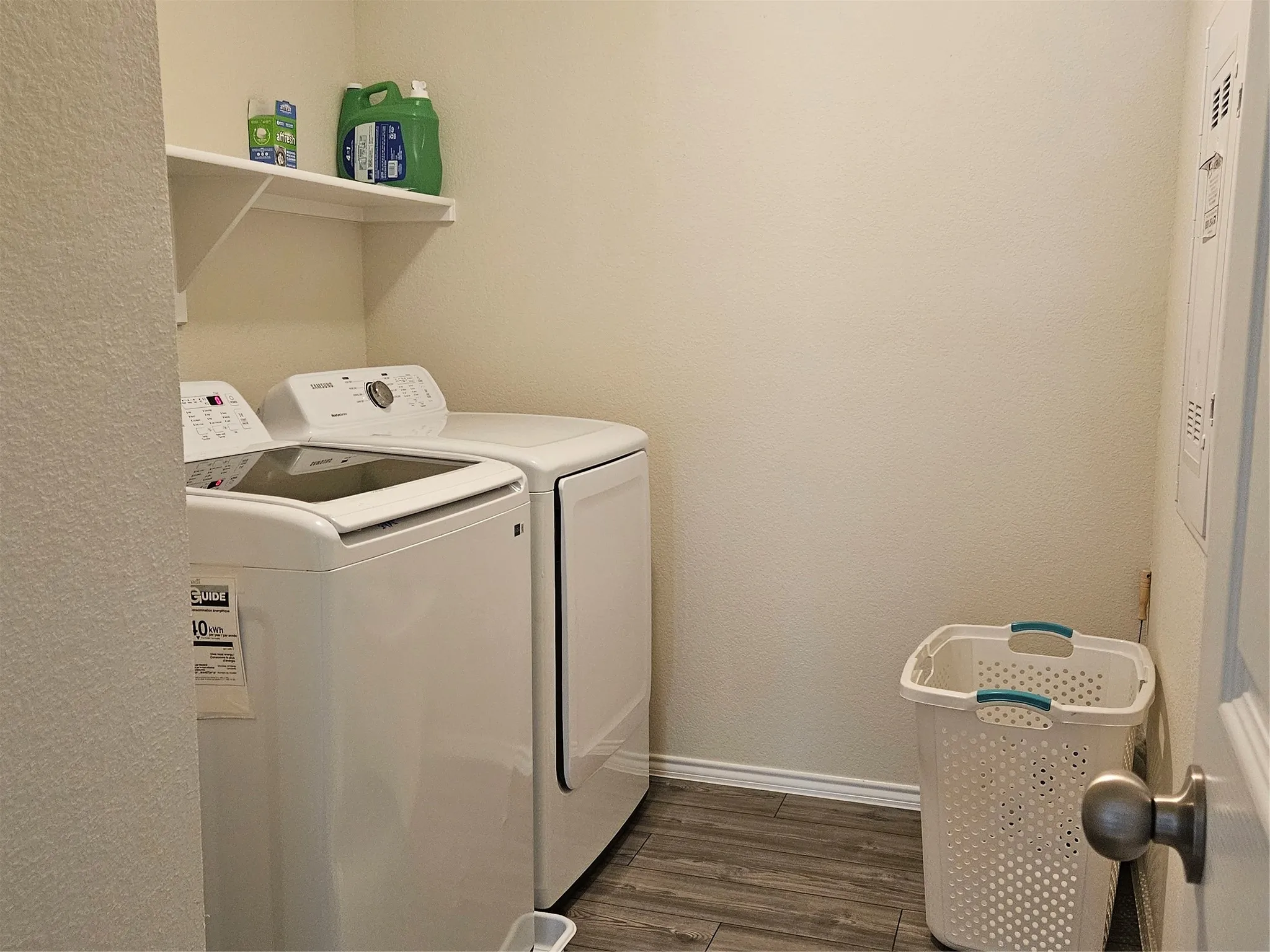 Dedicated utility area featuring wood-finish flooring and an integrated wall-mounted shelf