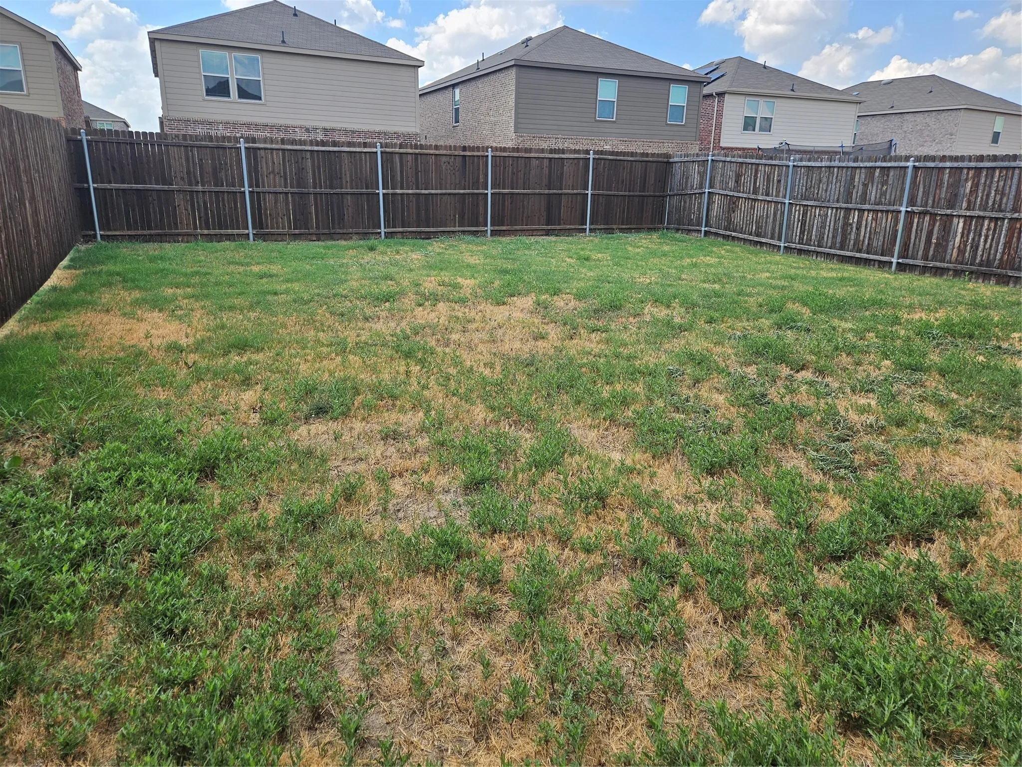 Open backyard featuring a full-perimeter wood privacy fence and lawn space