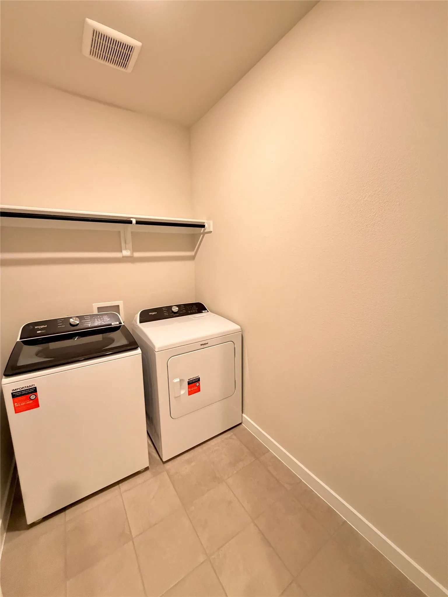 Utility space featuring neutral tile flooring, light-toned wall finish, and a wall-mounted shelving unit