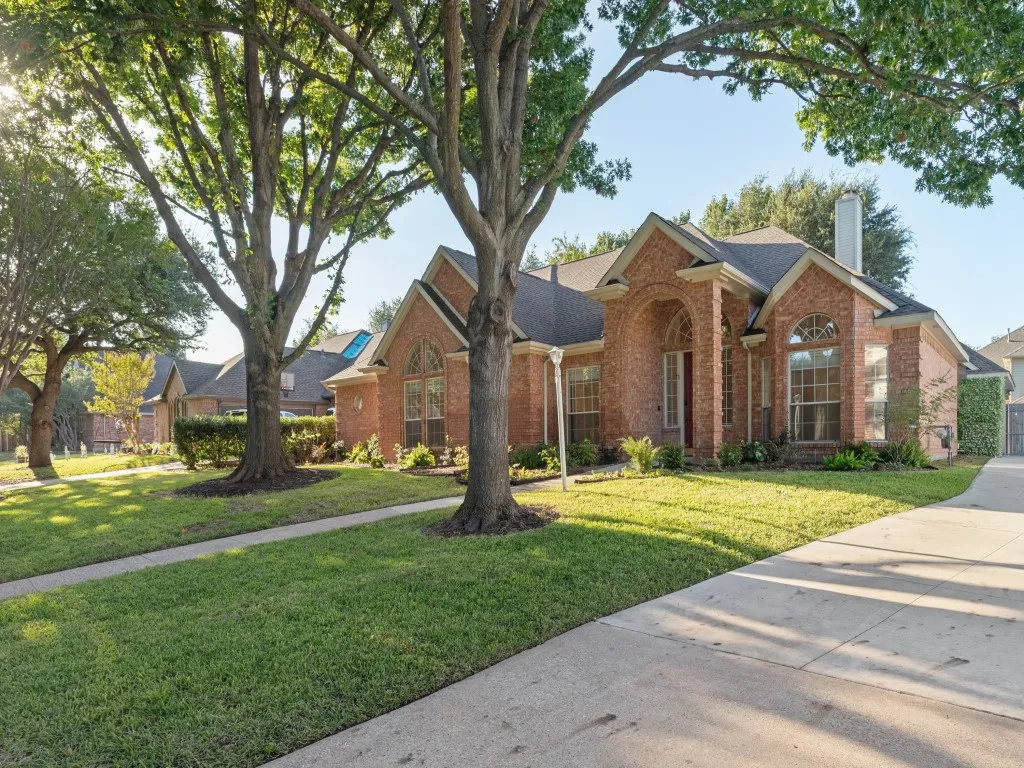 Brick exterior featuring a gabled roofline, arched entryway, multi-pane windows, and a concrete driveway