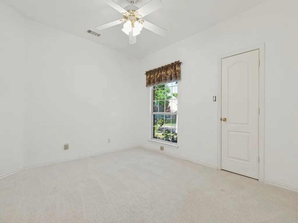Neutral-toned wall-to-wall carpeting, single-hung window with natural light, and ceiling-mounted fan with integrated light fixture