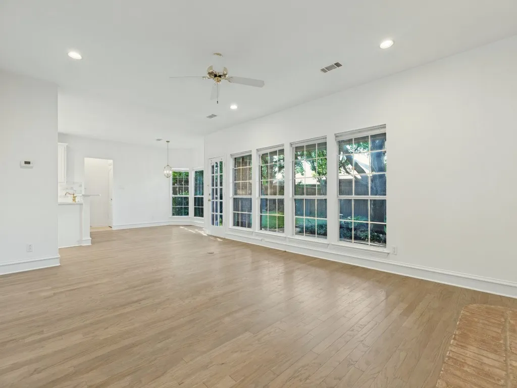 Open interior space featuring wood-finish flooring, recessed lighting, ceiling fan, and large-paned windows