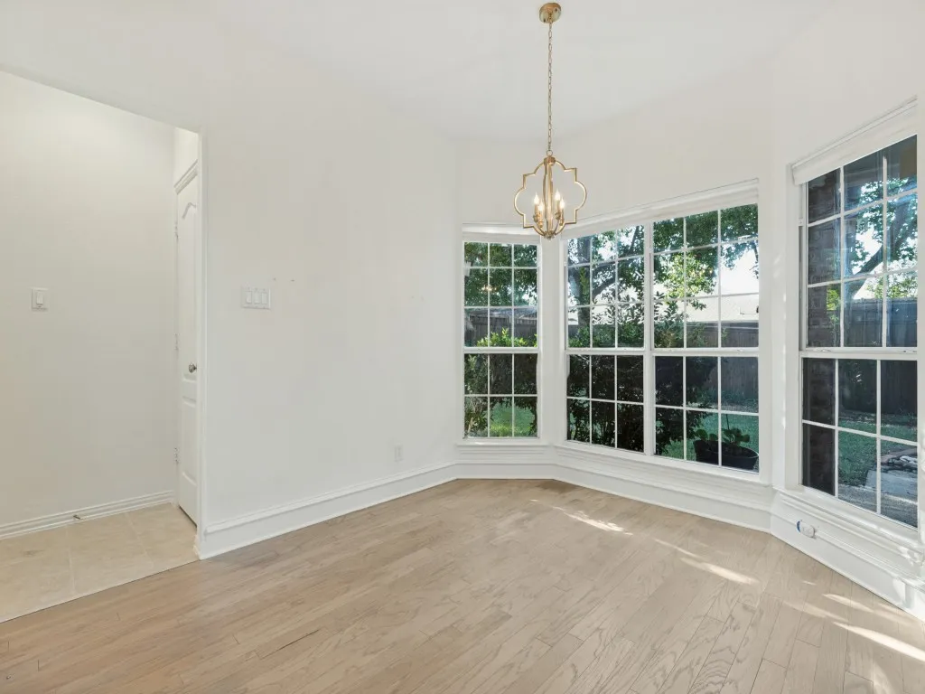 Bay window featuring grid-pattern panes, wood-finish flooring, and a decorative gold-tone pendant light fixture