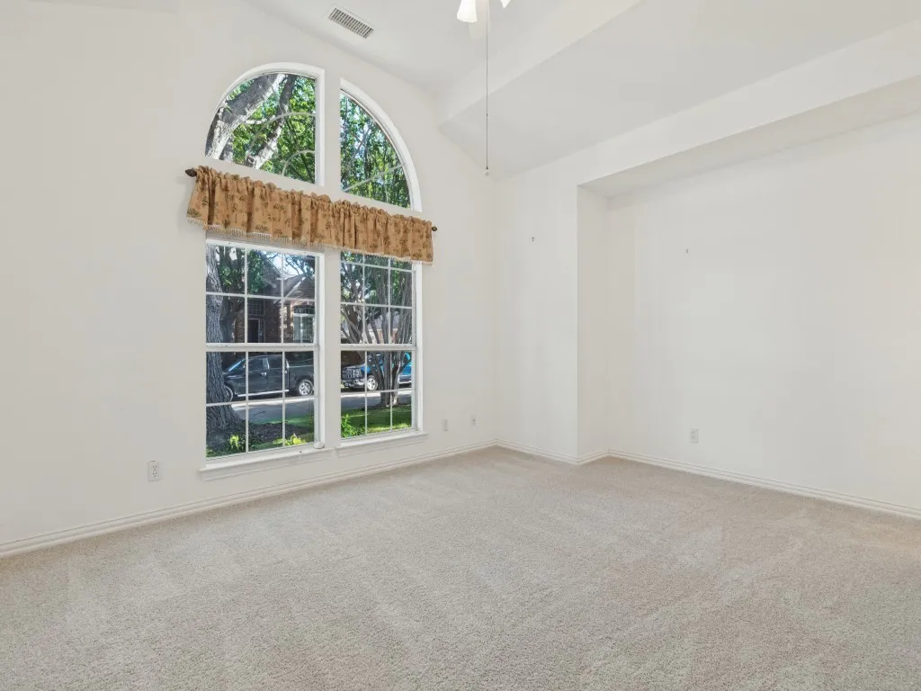 High ceilings featuring an arched window, white walls, and carpeted flooring