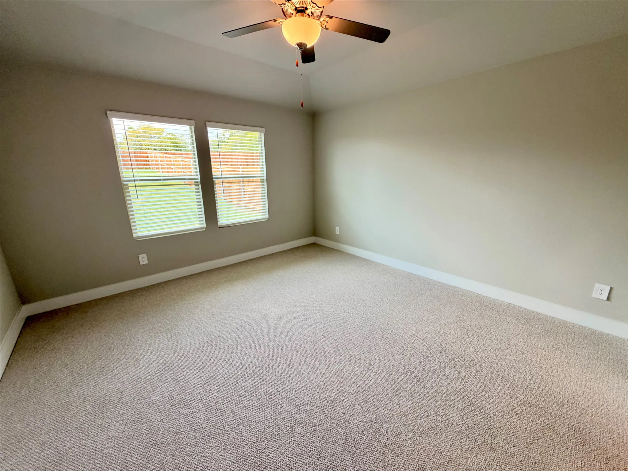 Vaulted ceiling with an integrated ceiling fan, neutral wall finishes, carpeted flooring, and dual windows