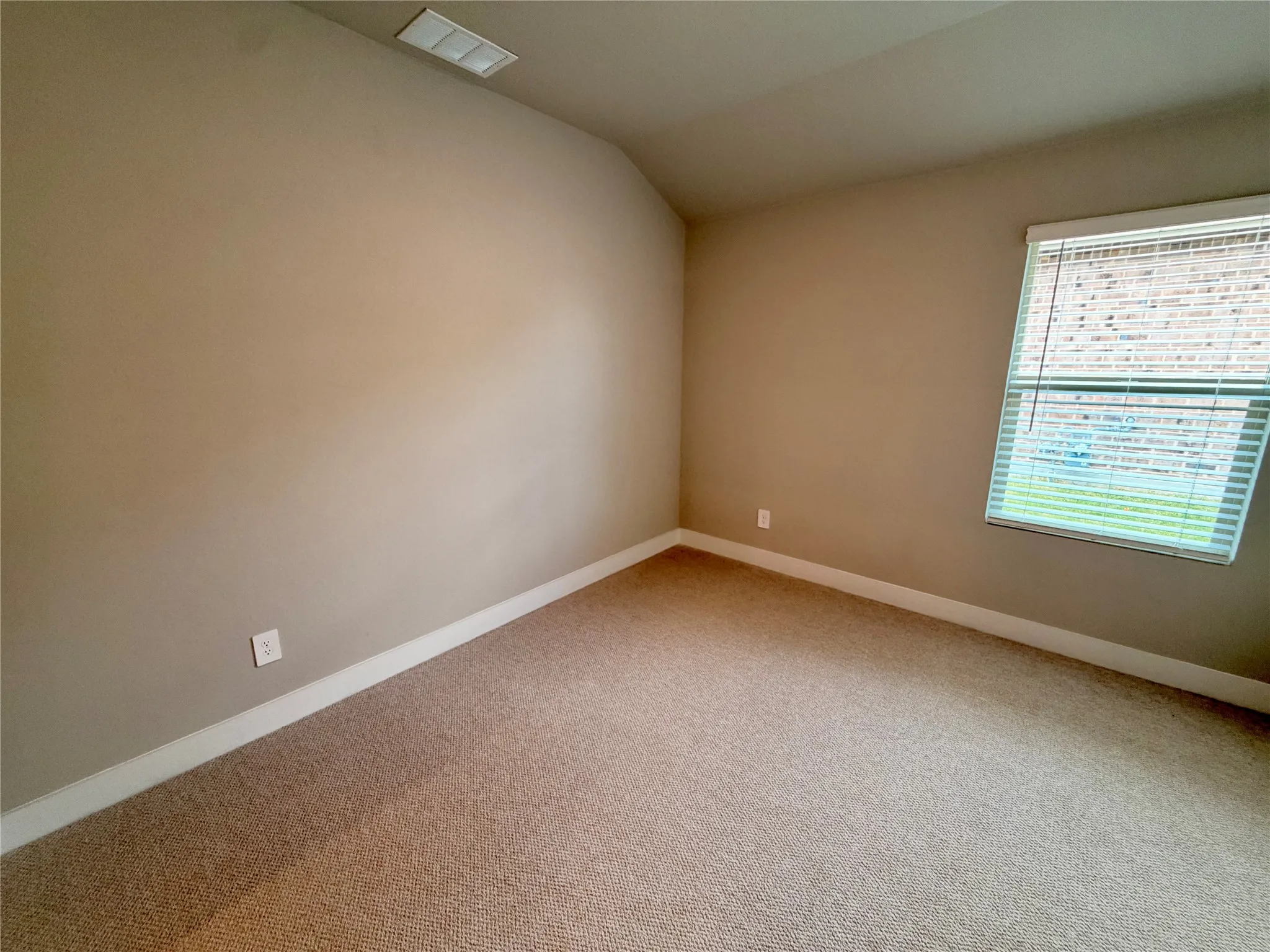 Neutral-toned room featuring high vaulted ceilings, wall-to-wall carpeting, and a single-pane window with horizontal blinds