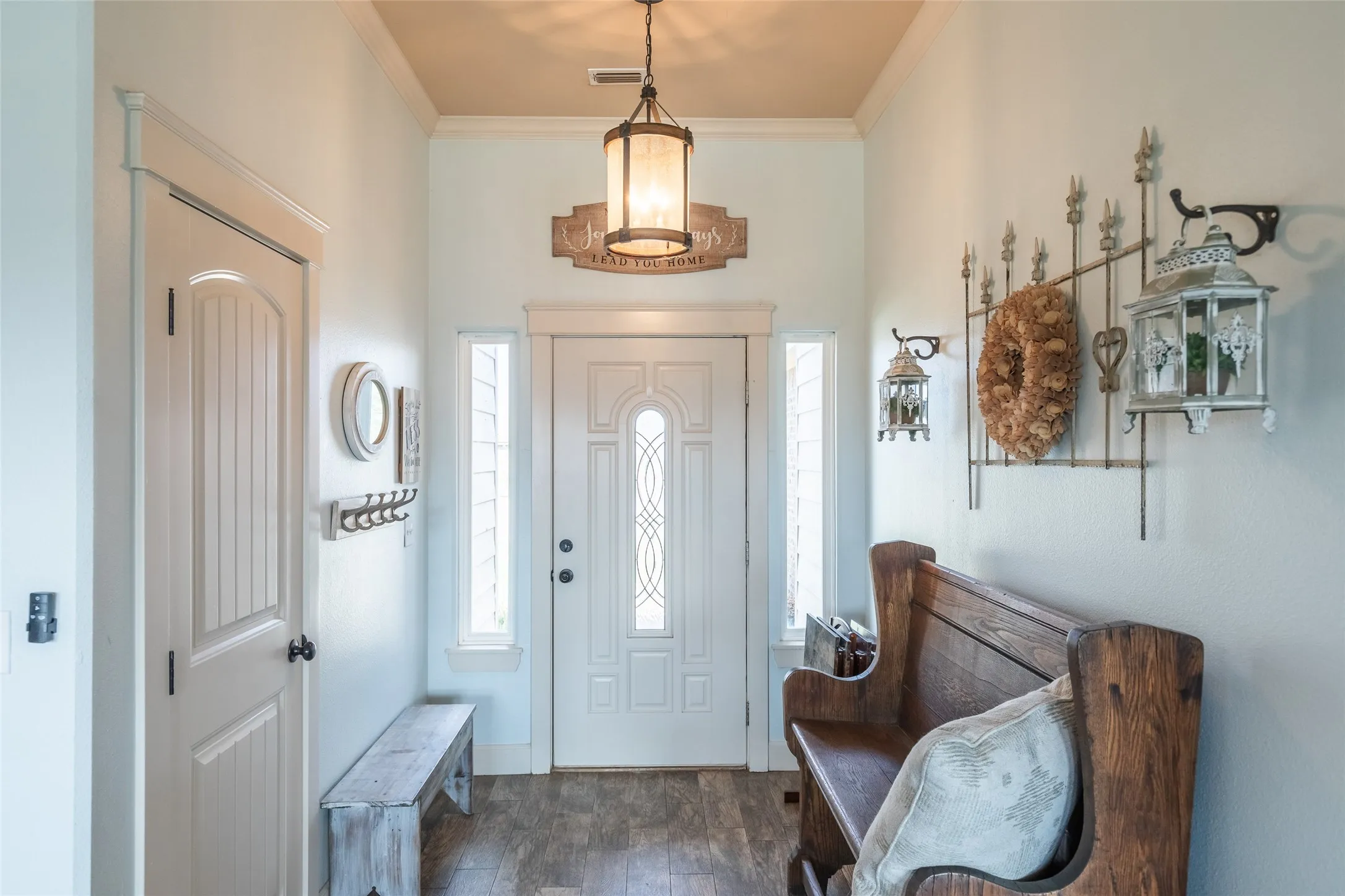 Entryway featuring high ceilings, wood-finish flooring, a decorative glass-panel front door, flanking sidelight windows, and a hanging pendant light fixture