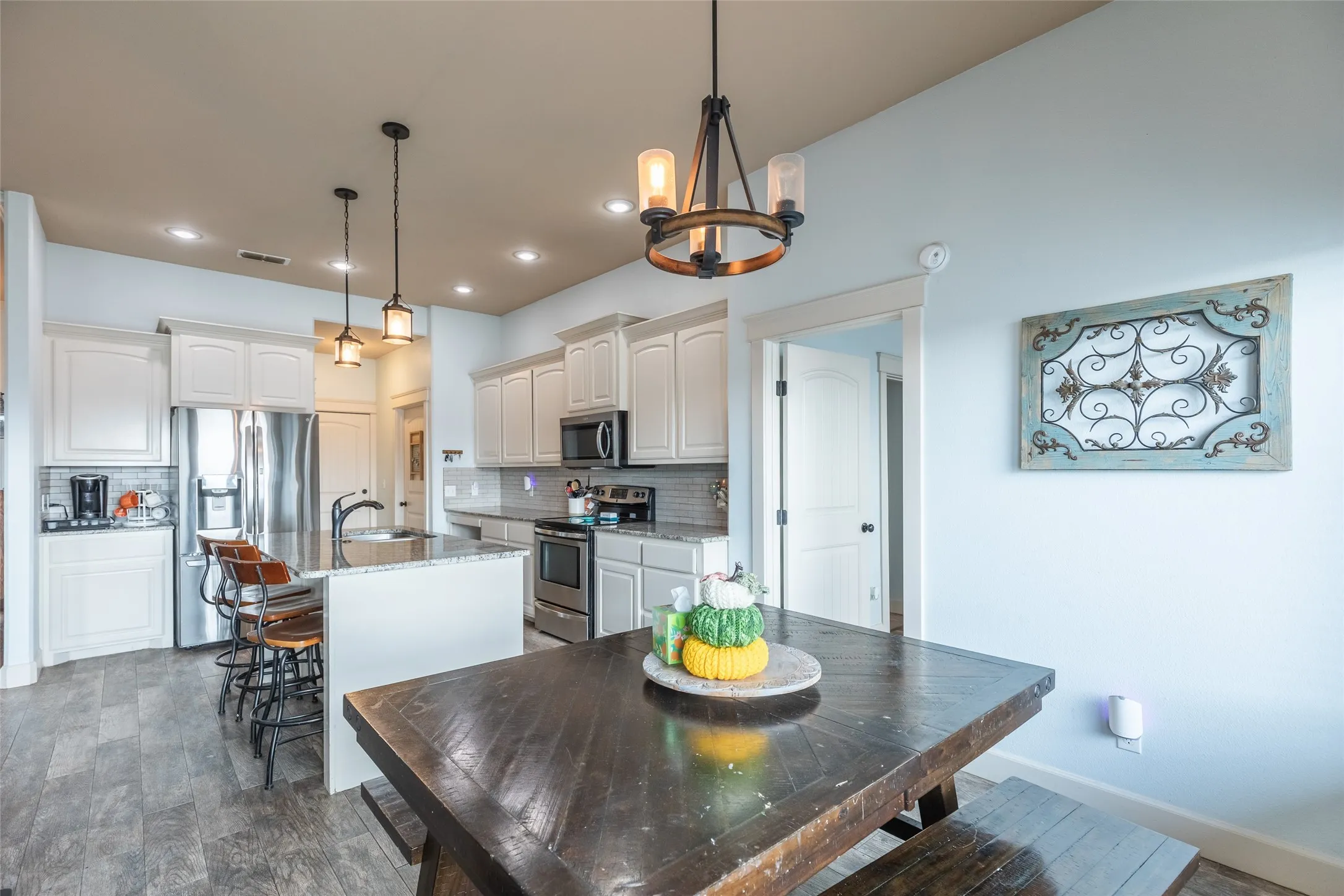 Kitchen featuring white cabinetry, stone-finish countertops, stainless steel appliances, wood-finish flooring, and pendant lighting