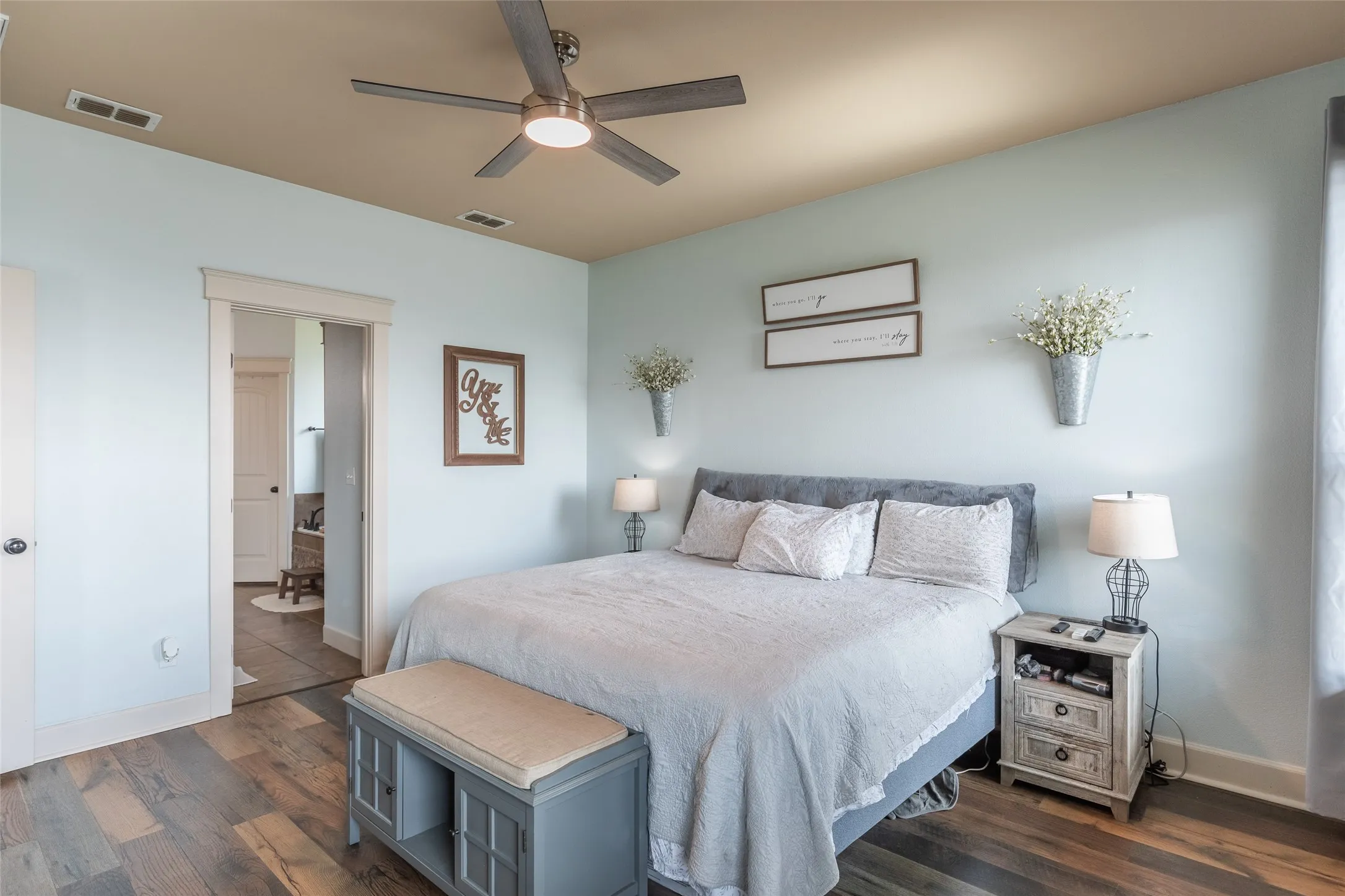 Bedroom featuring wood-finish flooring, a multi-tonal ceiling, and a central ceiling fan with integrated lighting