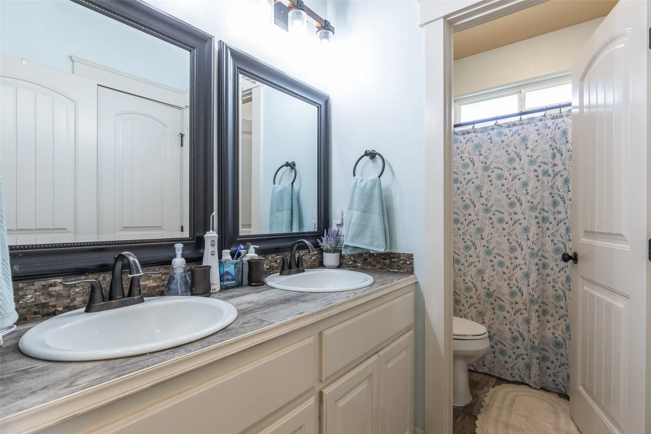 Double vanity featuring a wood-finish countertop, dual under-mount sinks, dark-toned faucets, and framed wall mirrors