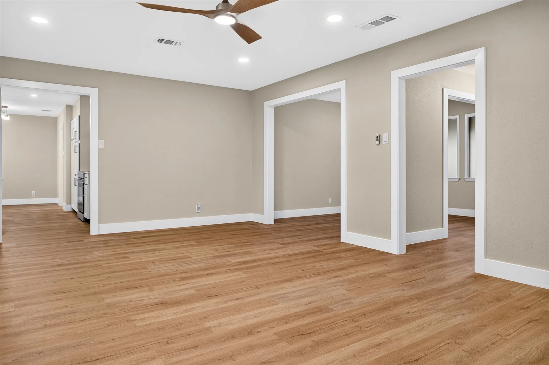 Neutral interior featuring wood-finish flooring, recessed lighting, and a modern ceiling fan