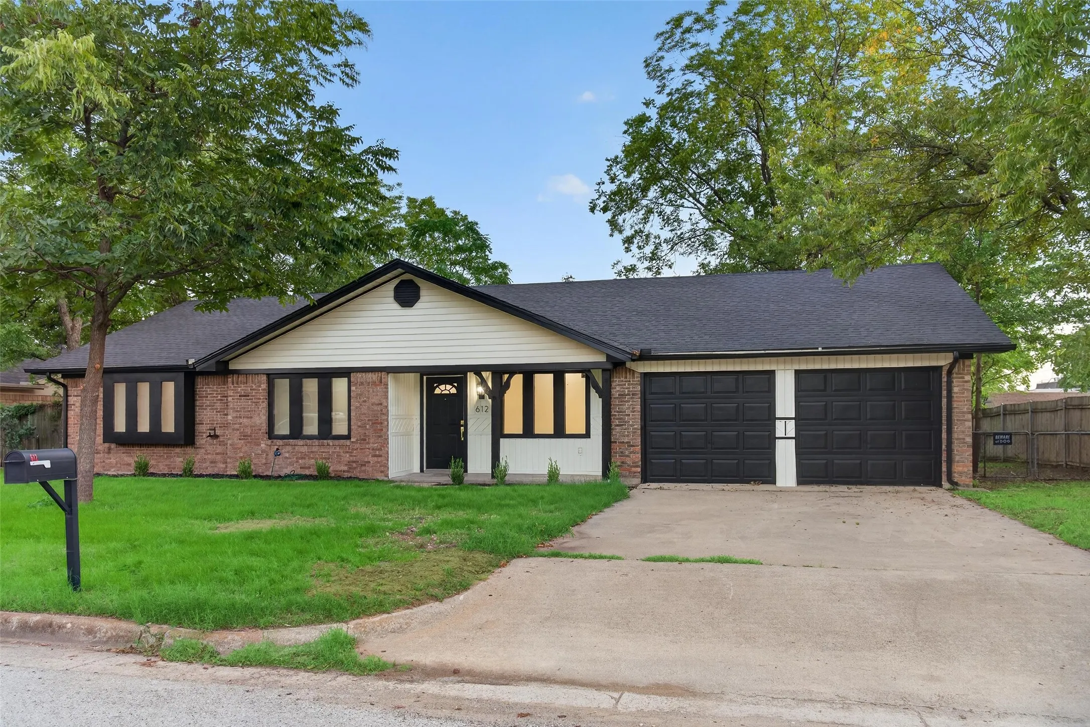 Single-story ranch exterior featuring a mixed masonry and horizontal siding facade, two-car garage with dark finish doors, covered front entryway, and dark window trim