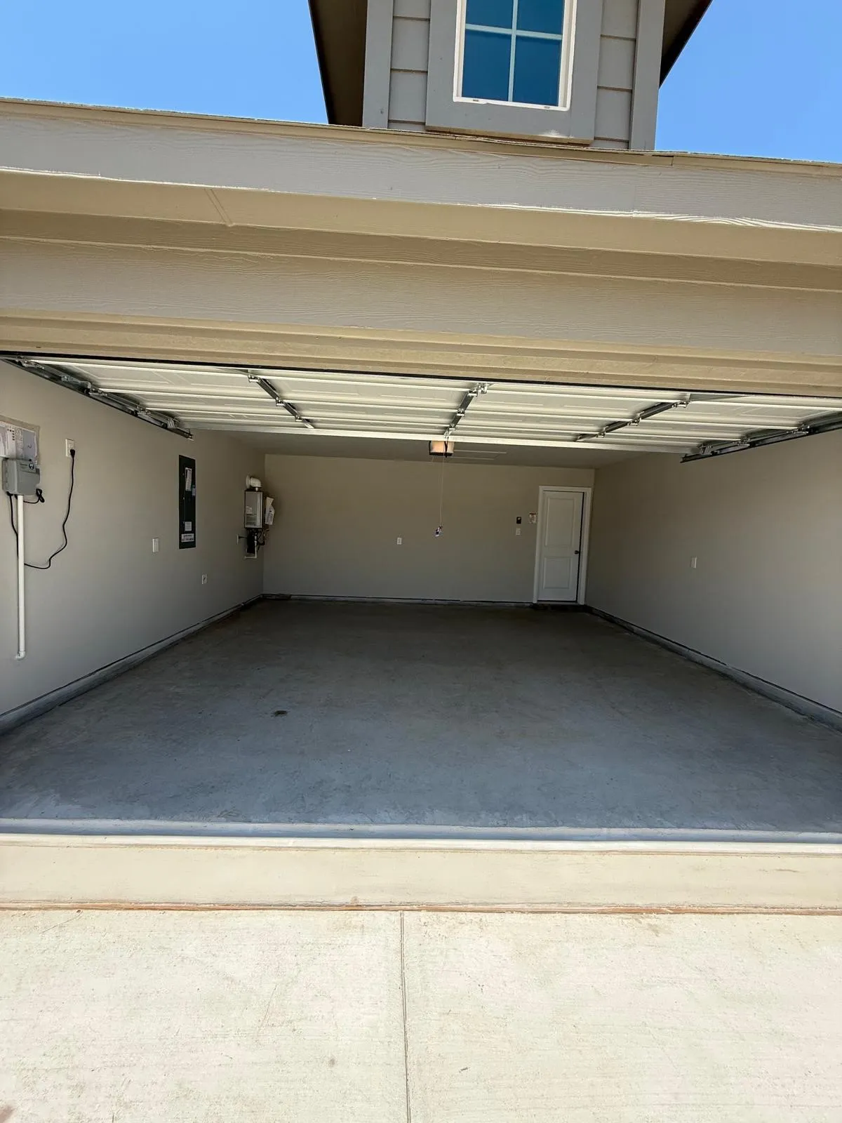 Multi-car garage featuring a concrete floor, finished walls, overhead door system, and a dedicated interior door