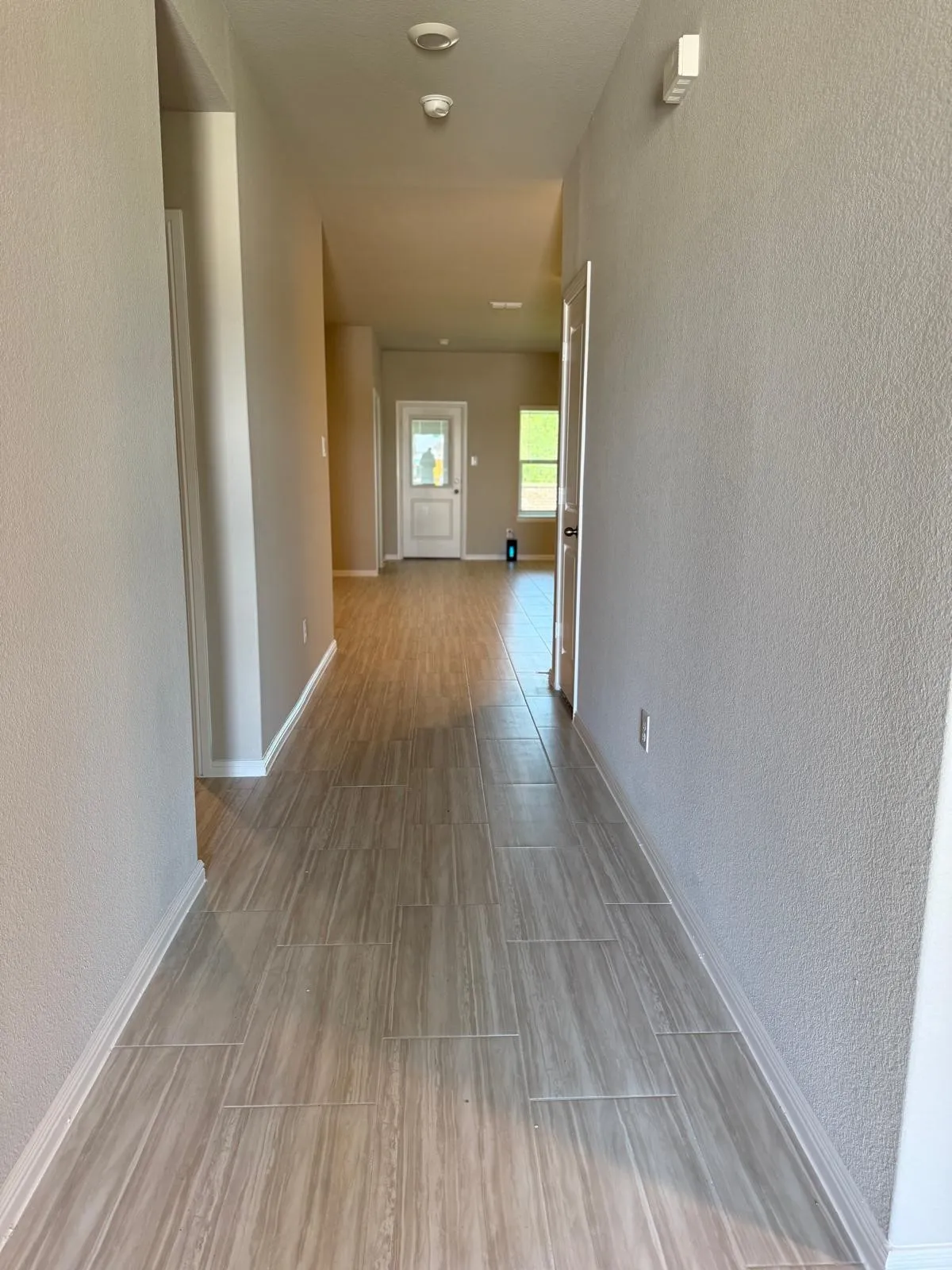 Hallway featuring wood-finish tile flooring, neutral wall paint, and an exterior door with glass insert