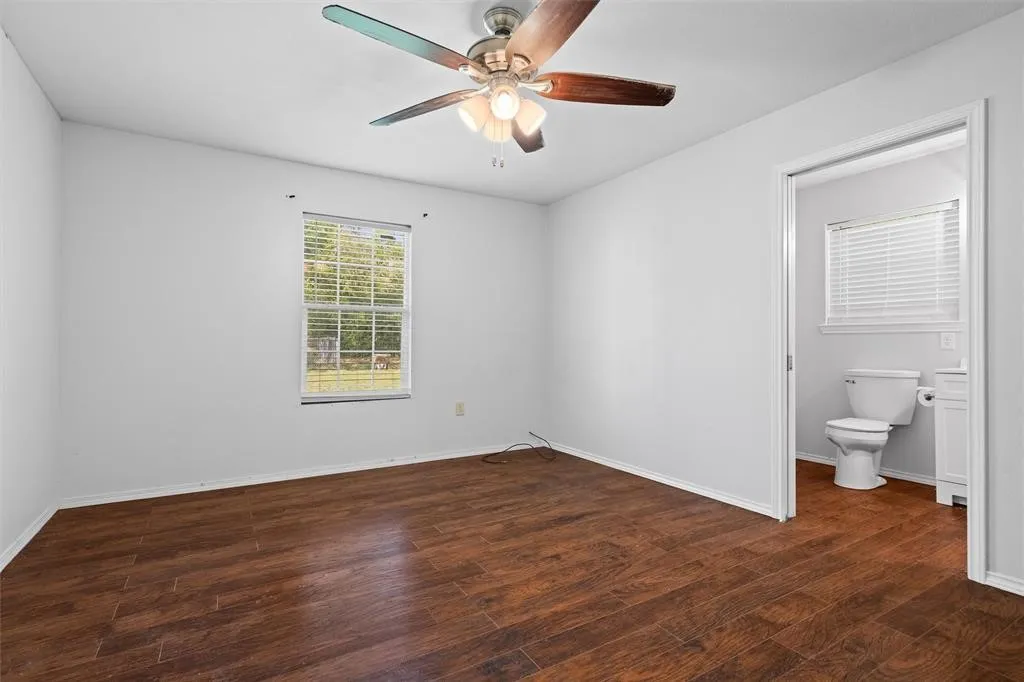 Wood-finish flooring, multi-blade ceiling fan with integrated lighting, and single-hung window with horizontal blinds