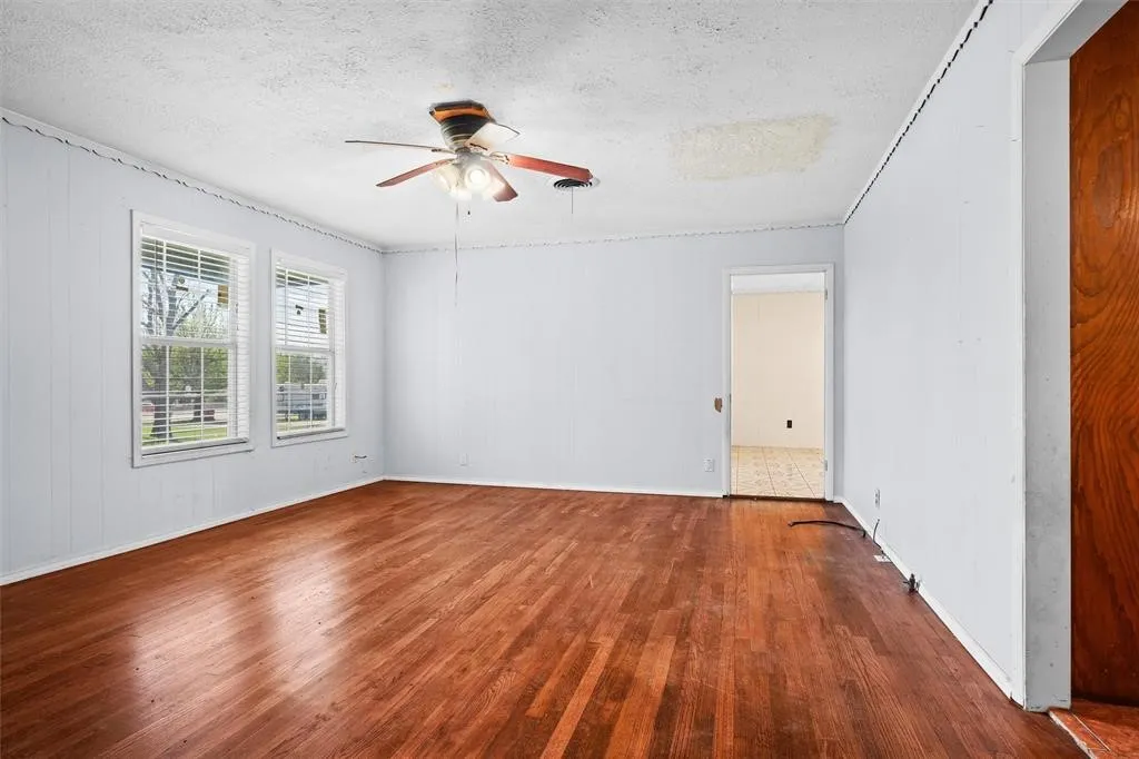 Interior space featuring wood-finish flooring, two large windows, and a ceiling-mounted light fixture with a fan