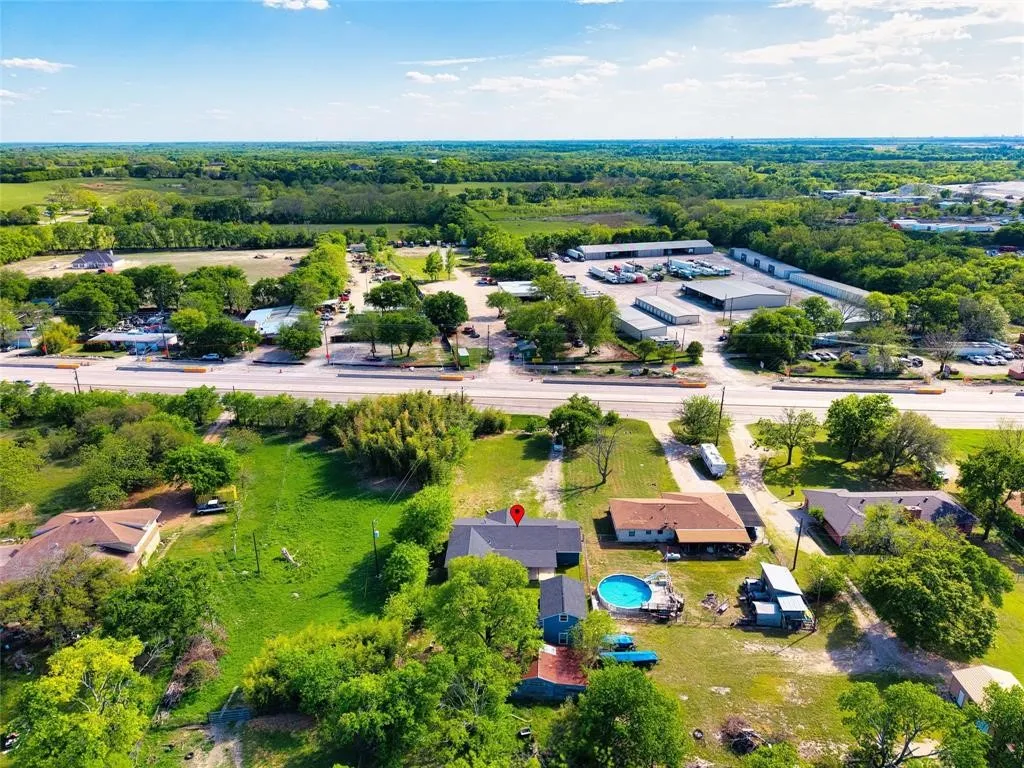 Aerial perspective of a property featuring expansive green space, mature trees, a detached secondary structure, and a circular above-ground pool
