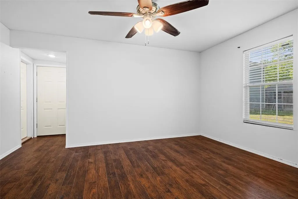 Room featuring wood-finish flooring, a multi-pane window with blinds, and a ceiling fan with integrated lighting