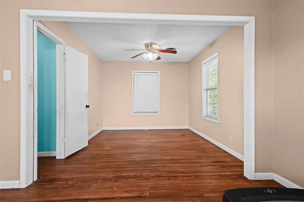 Room featuring wood-finish flooring, a ceiling fan with integrated lighting, and dual windows