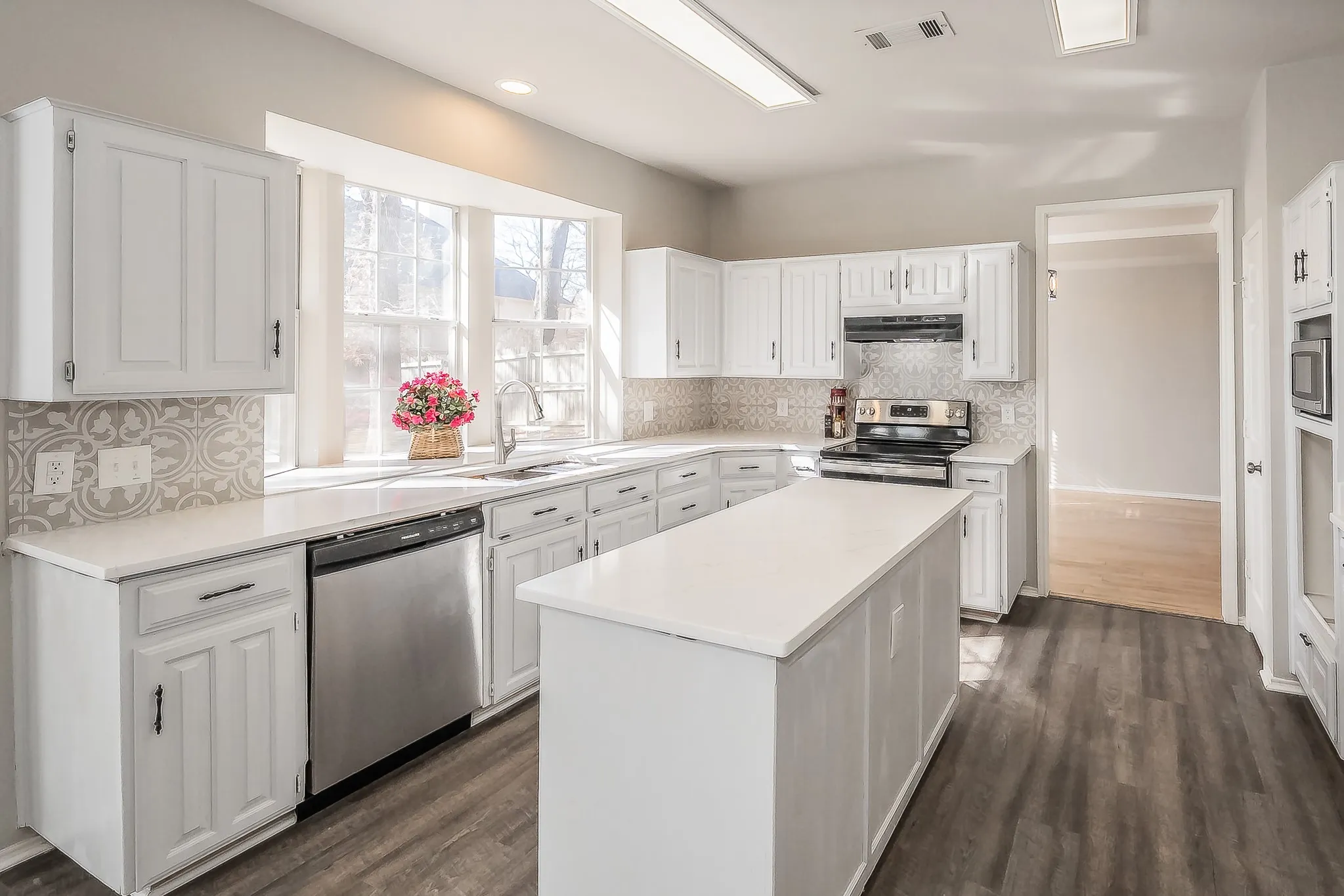 Kitchen featuring quartz counters, white cabinets, and stainless steel appliances.  Bay window offers plenty of natural lighting  & great place for growing herbs!