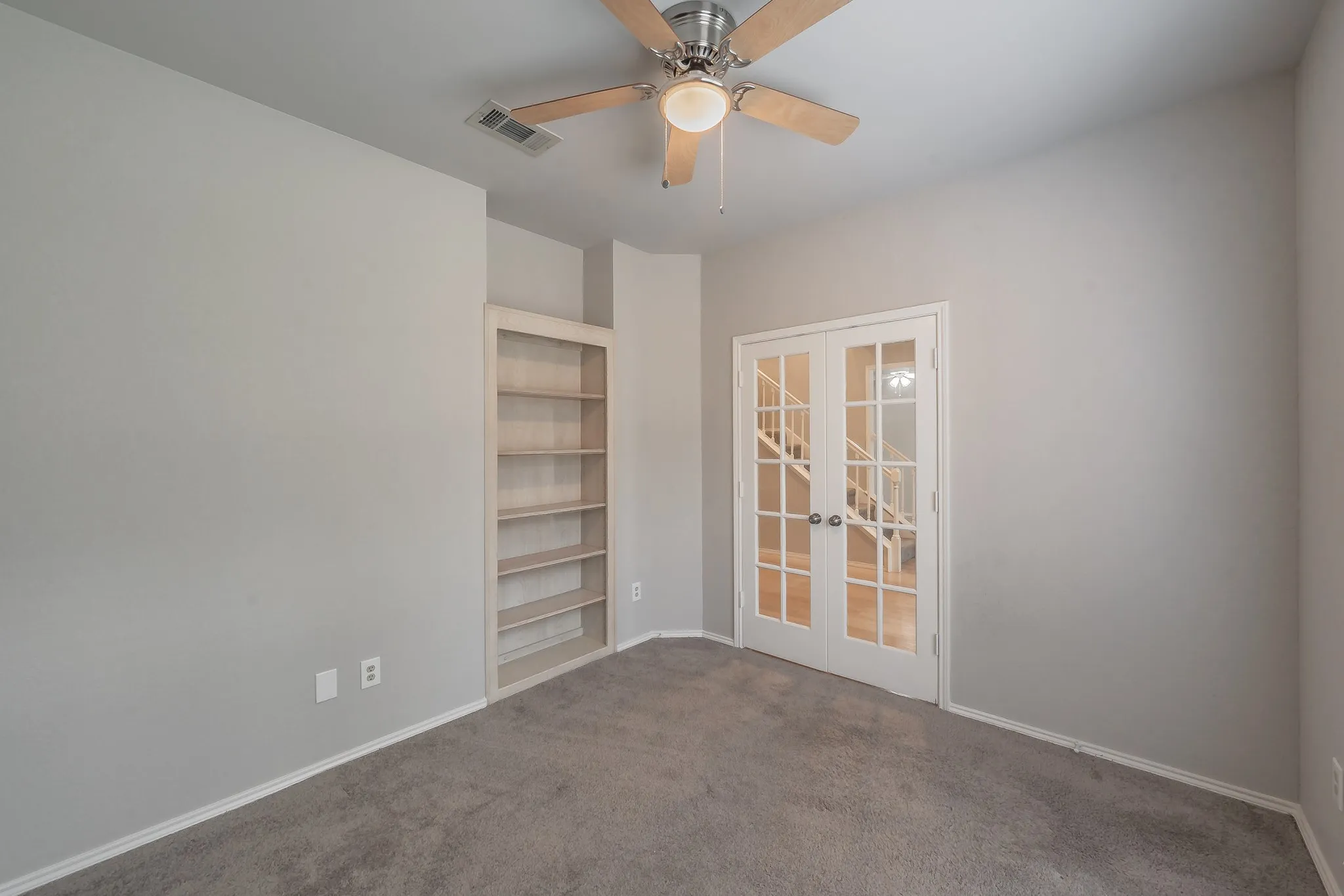 Office on main floor with built in bookshelves and French doors.