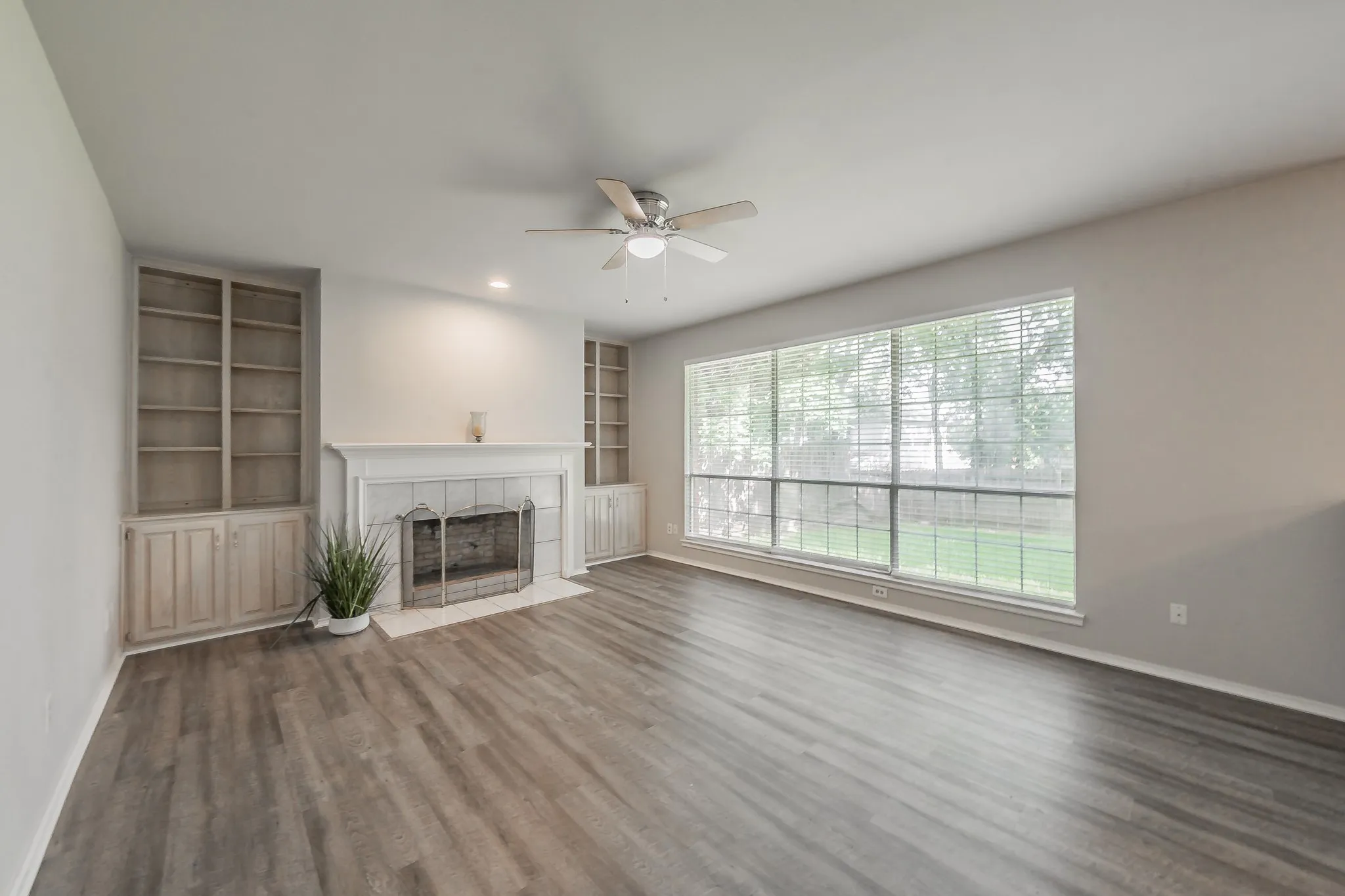 Spacious family room offering a wall of windows for abundant natural lighting, ceiling fan and vinyl wood look flooring.
