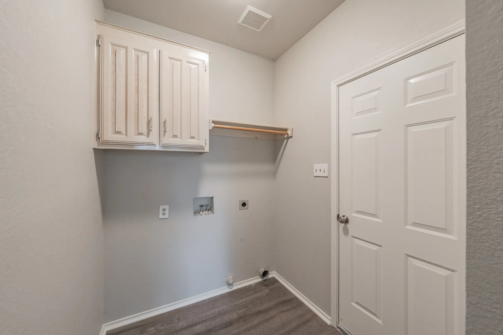 Laundry room with cabinets for added storage leading into two car garage.