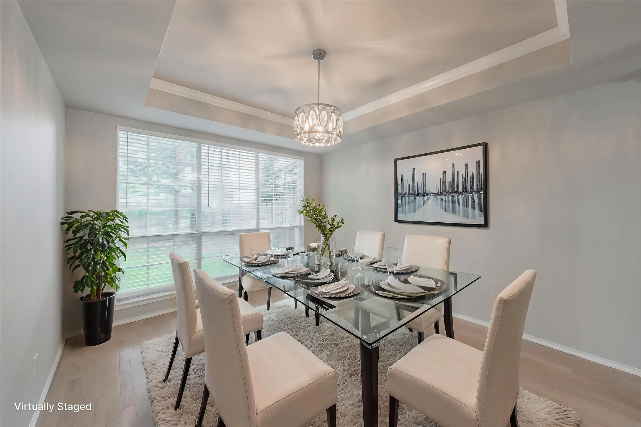 Virtually staged formal dining room boasting tray ceiling with updated light.