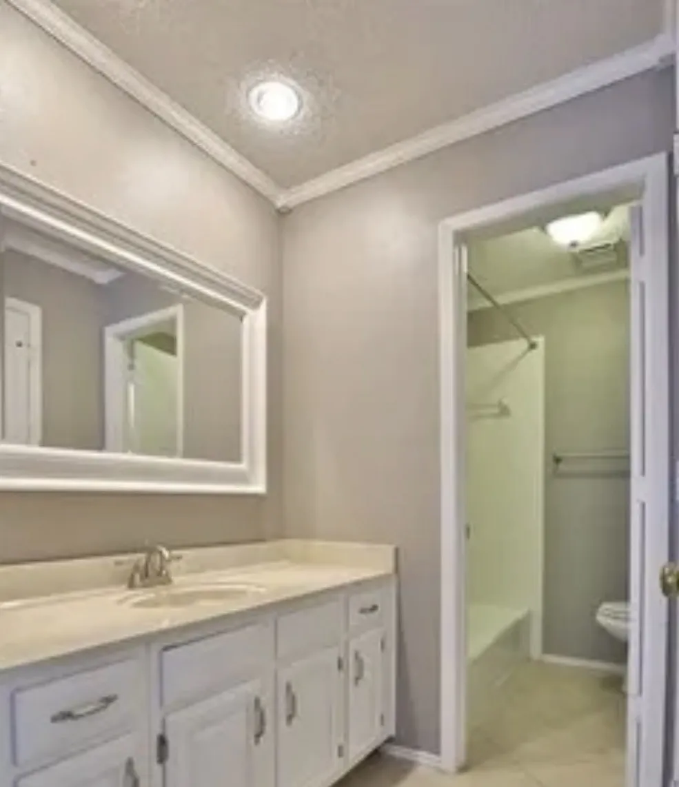 Bathroom featuring a white vanity cabinet with chrome hardware, an integrated sink, a framed wall mirror, crown molding, and recessed lighting