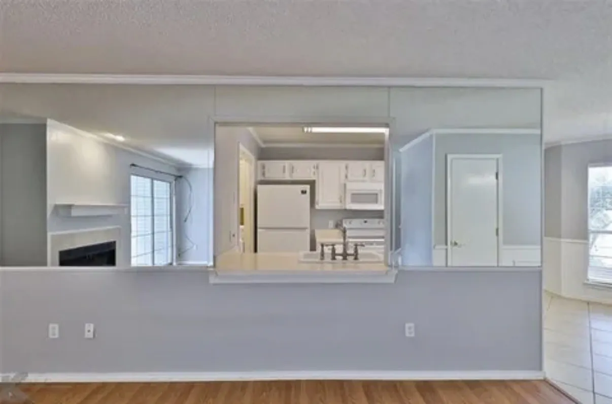 Pass-through window featuring a service counter, full-wall mirrors, wood-finish flooring, and white cabinetry