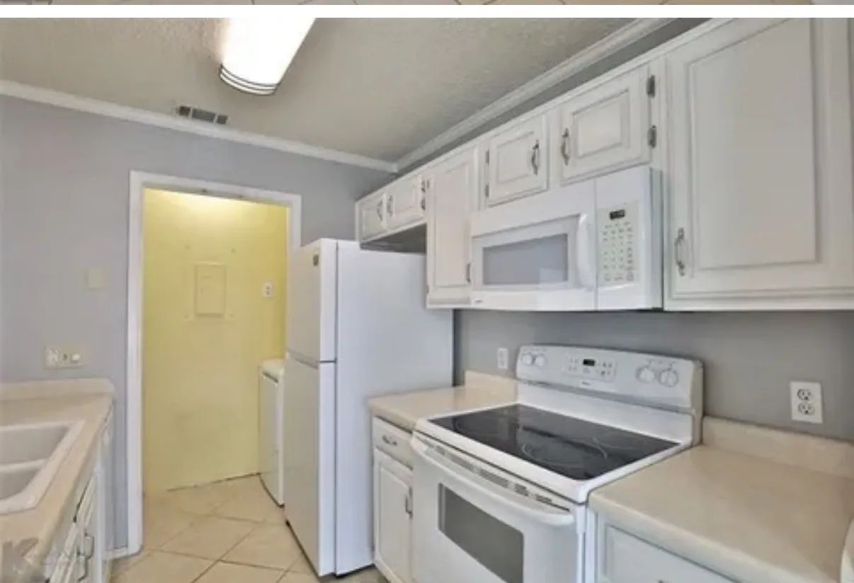 Kitchen featuring white cabinetry, integrated white appliances, solid-surface countertops, and tile flooring