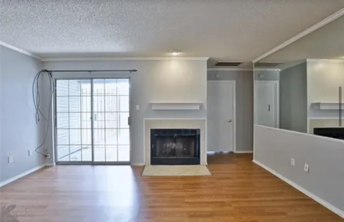 Living area featuring wood-finish flooring, a fireplace with a mantel, sliding glass patio doors, and a full-length wall mirror