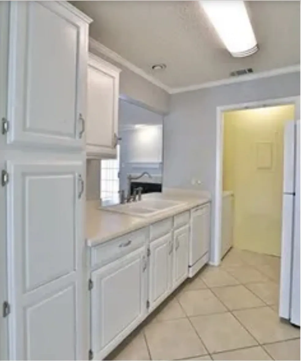 Kitchen featuring white cabinetry, solid-surface countertops, a double-basin sink with a gooseneck faucet, tile flooring, and flush-mount lighting