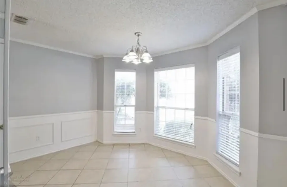 Dining area featuring tile flooring, wainscoting, a multi-light chandelier, and large windows with integrated blinds