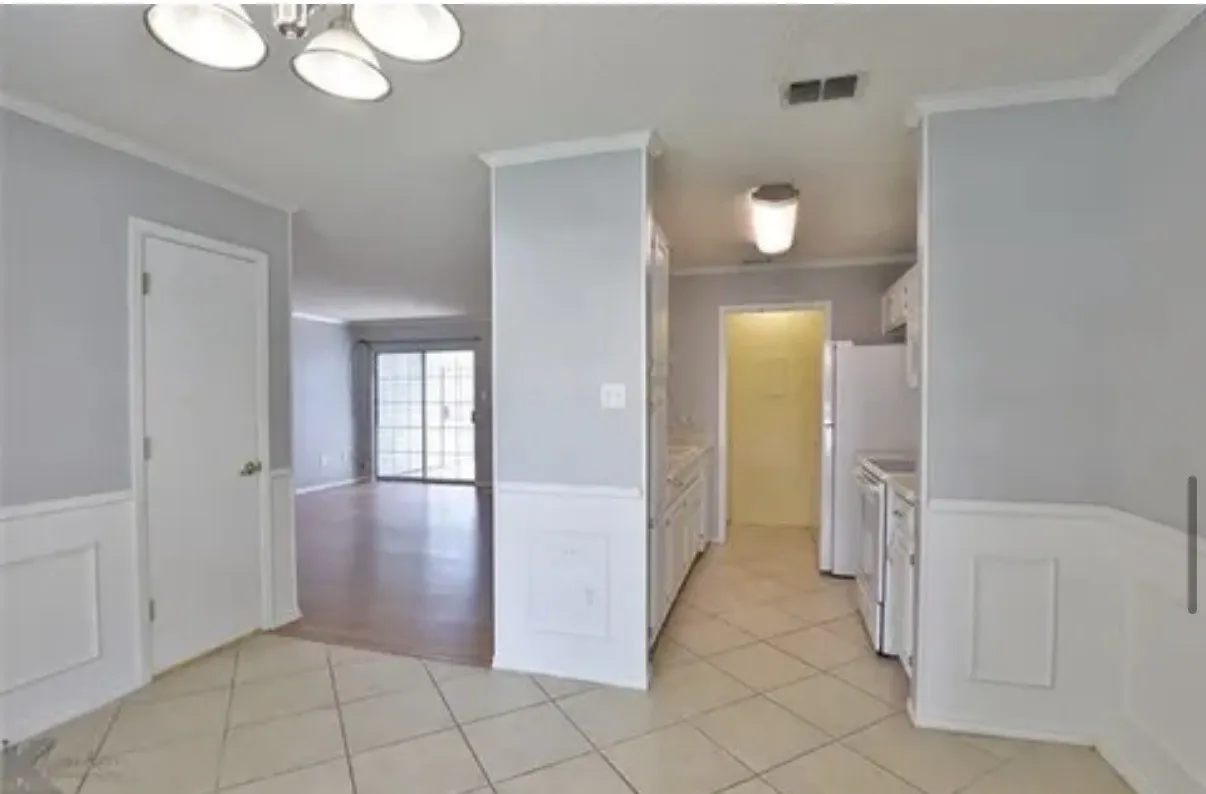 Neutral interior featuring light-toned tile flooring, wainscoting, built-in cabinetry, and multi-light ceiling fixtures