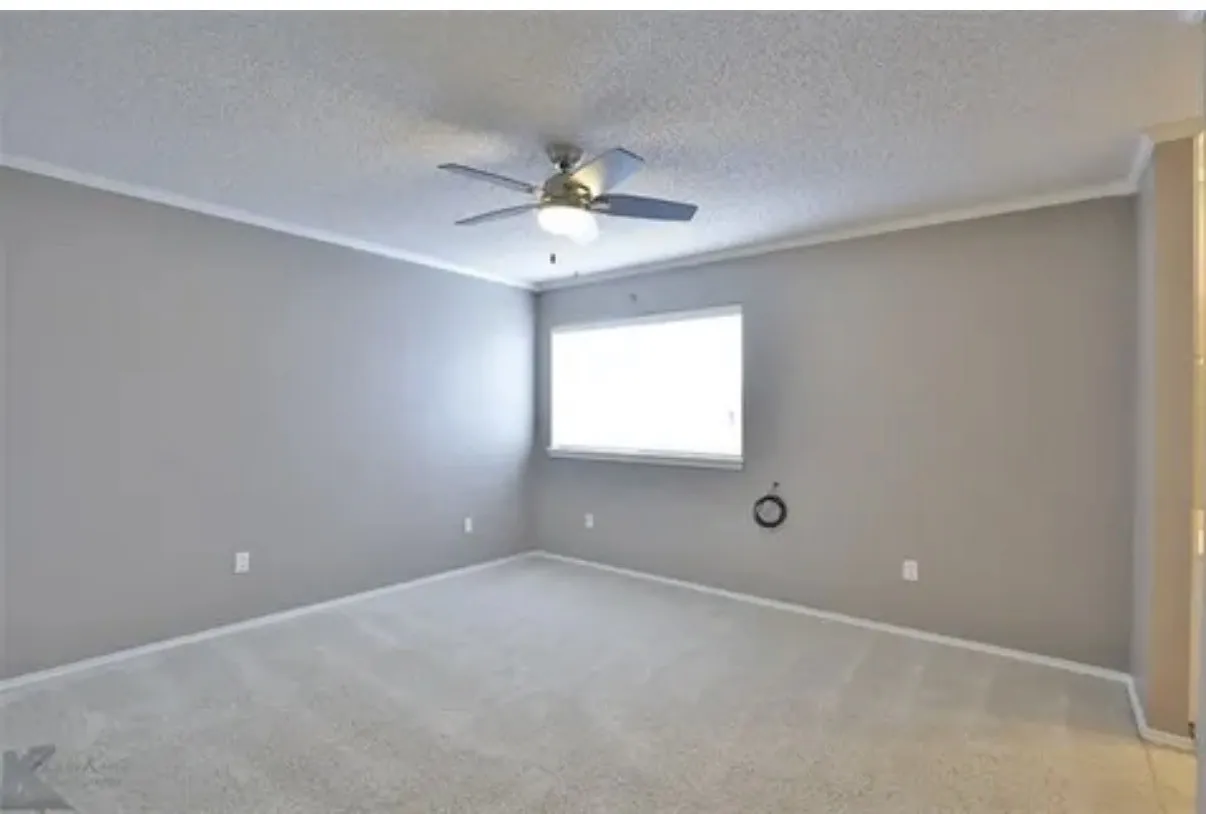Neutral-toned walls, wall-to-wall carpeting, window with natural light, and a ceiling fan with integrated lighting