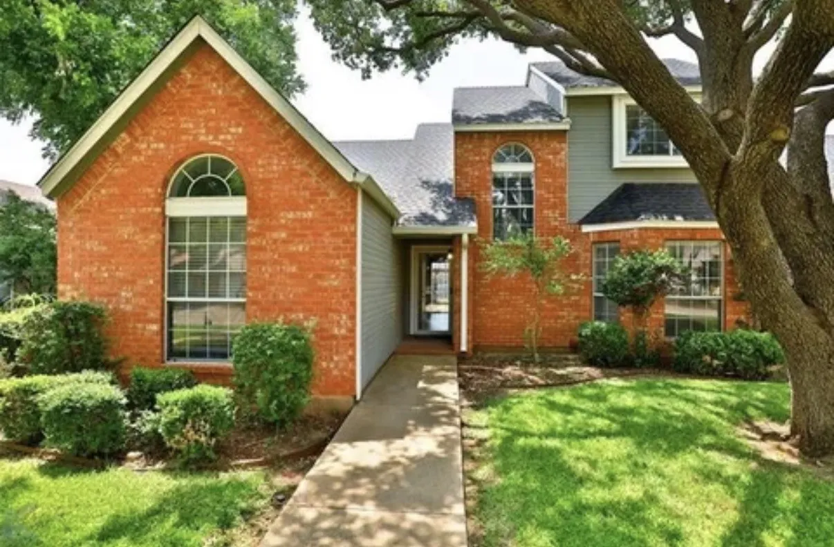 Exterior featuring brick masonry, arch-top windows, horizontal siding, and a paved walkway leading to the entry