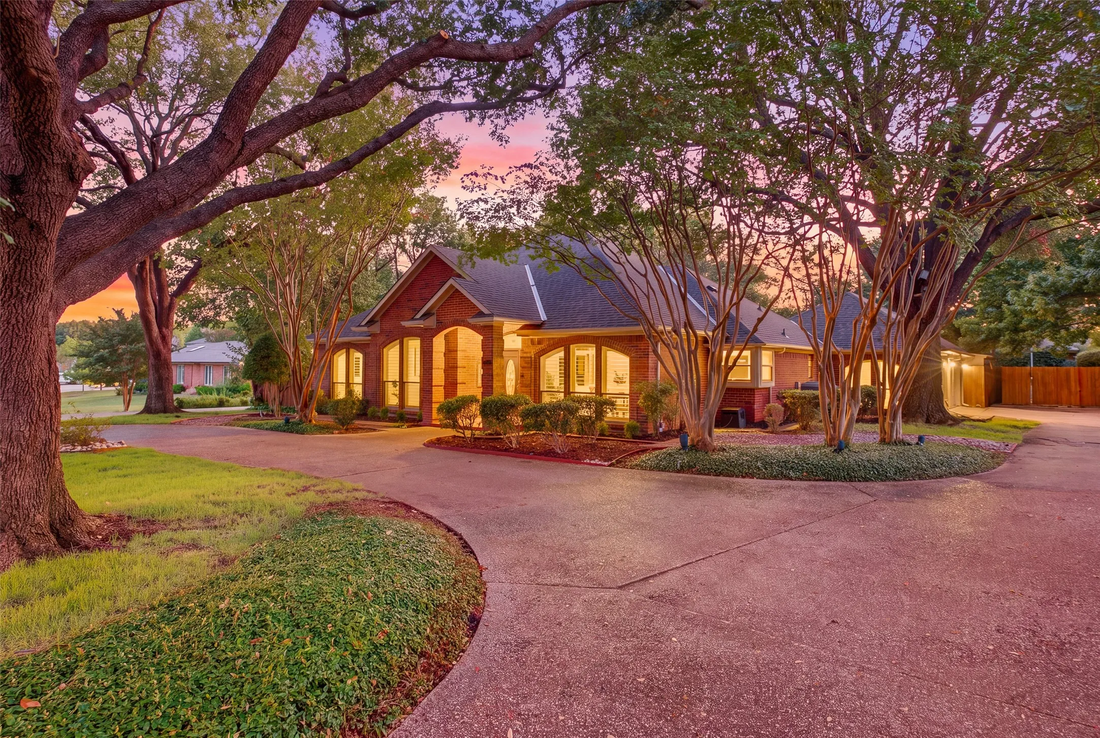 Curb appeal that sets the tone: lush landscaping, circular drive and a warm glow from every window.