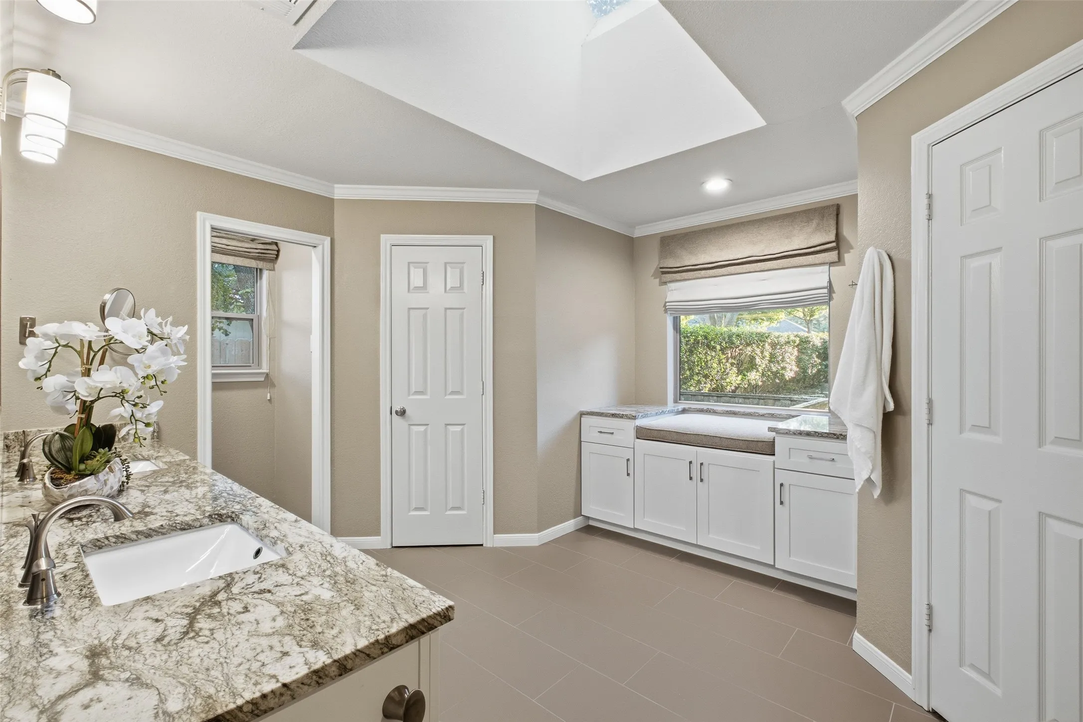 Spa-inspired primary bath with skylight, granite counters and a built-in window-seat nook.