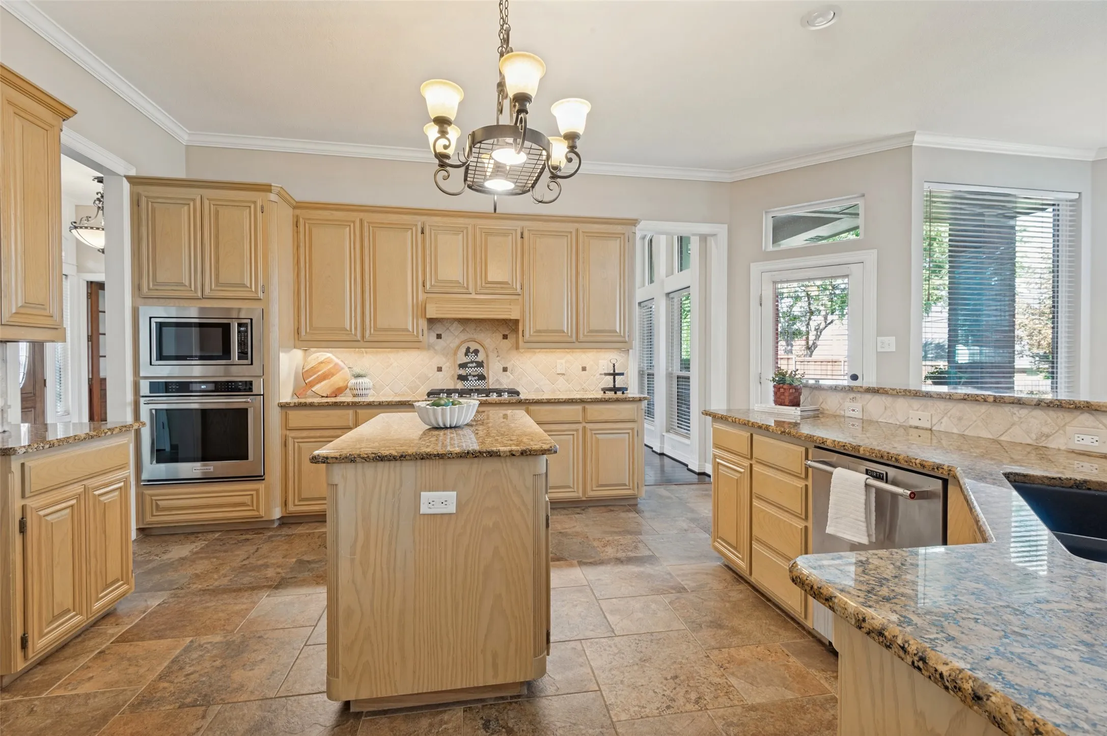 Kitchen featuring light-finish cabinetry, stone-style countertops, tile flooring, a central island, and stainless steel double wall ovens