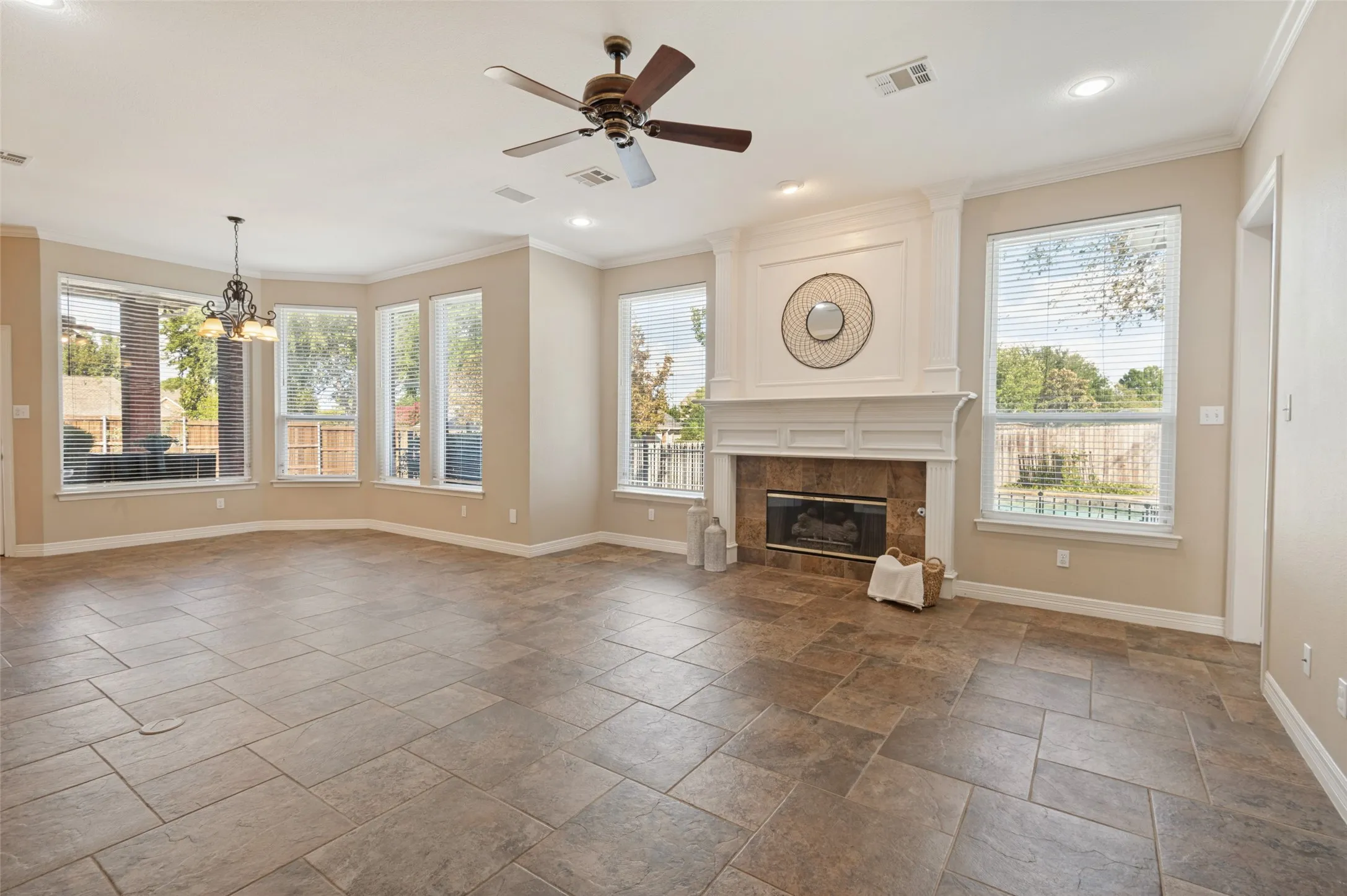 Open concept living space featuring stone-style tile flooring, multi-pane windows, a fireplace with decorative millwork mantel, and recessed lighting