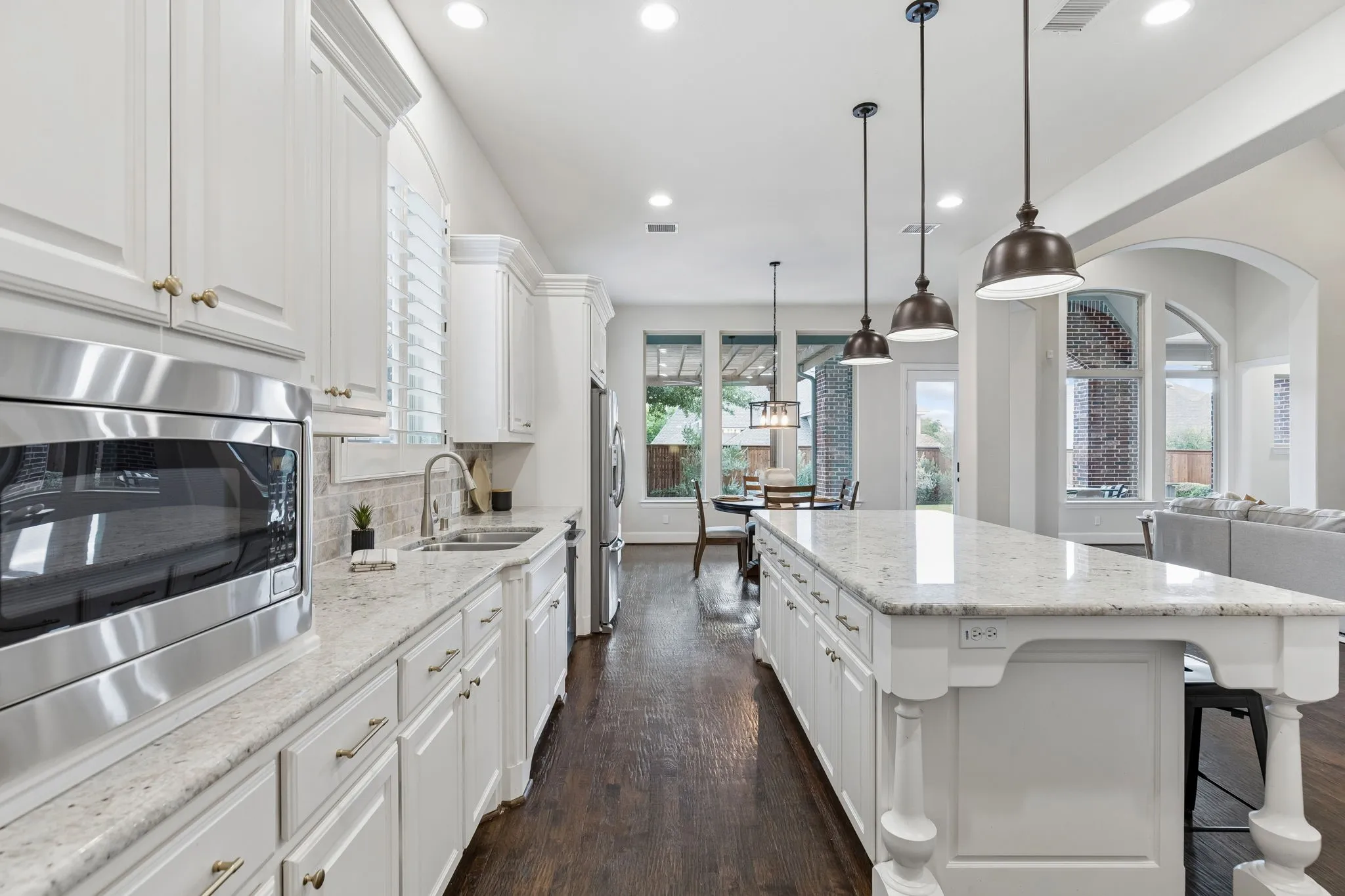 Kitchen featuring white cabinetry, stone countertops, a central island with decorative legs, stainless steel appliances, and wood-finish flooring