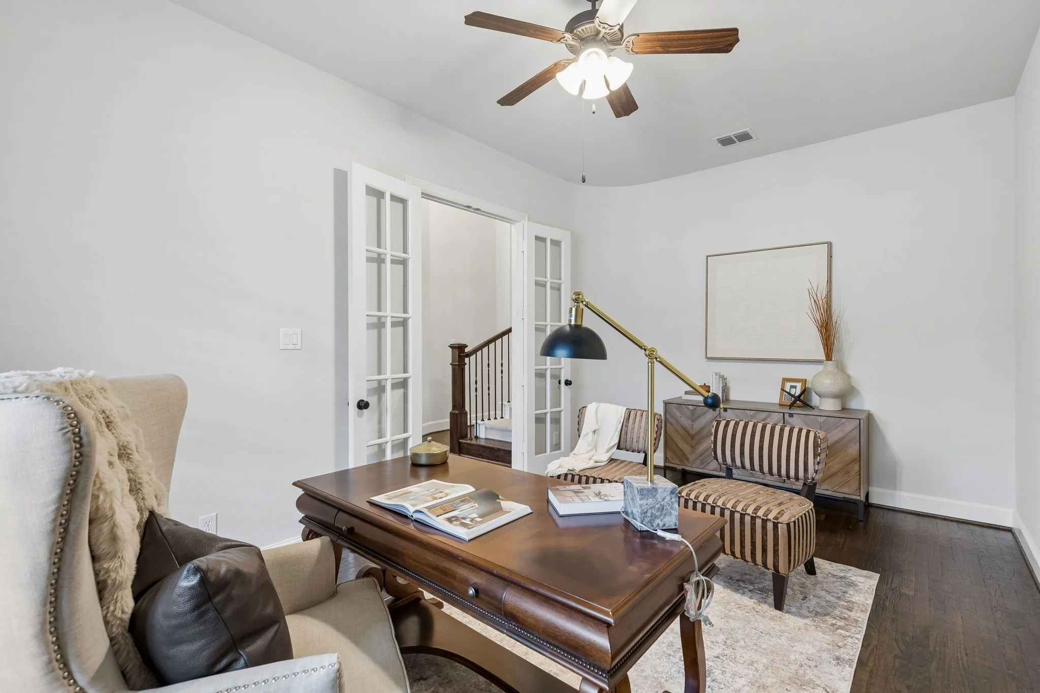 Room featuring dark wood-finish flooring, white French doors, and a ceiling fan with integrated light fixture